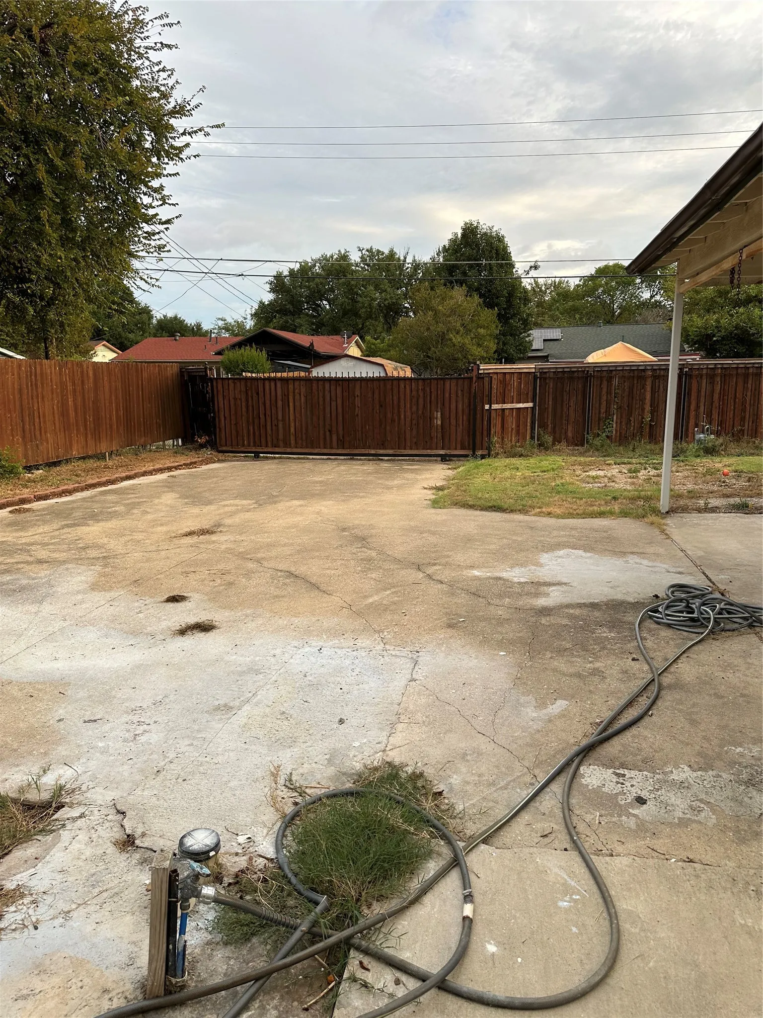Concrete patio area with a wood-stained privacy fence and mature perimeter trees