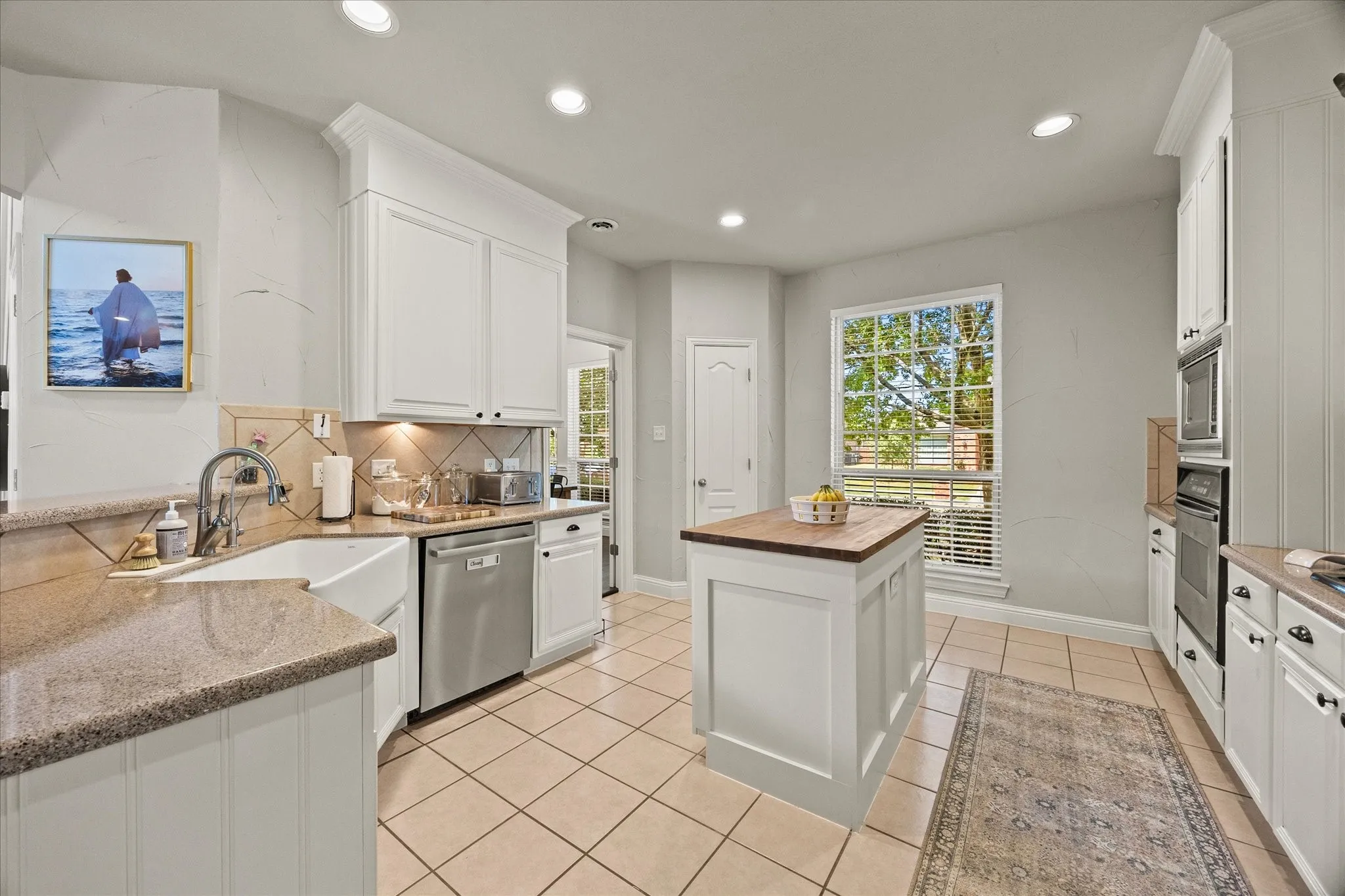 1602 Mapleleaf Drive Wylie, TX 75098 Kitchen featuring white shaker cabinetry, an apron front sink, tile flooring, a center island with a wood-finish top, and stainless steel appliances