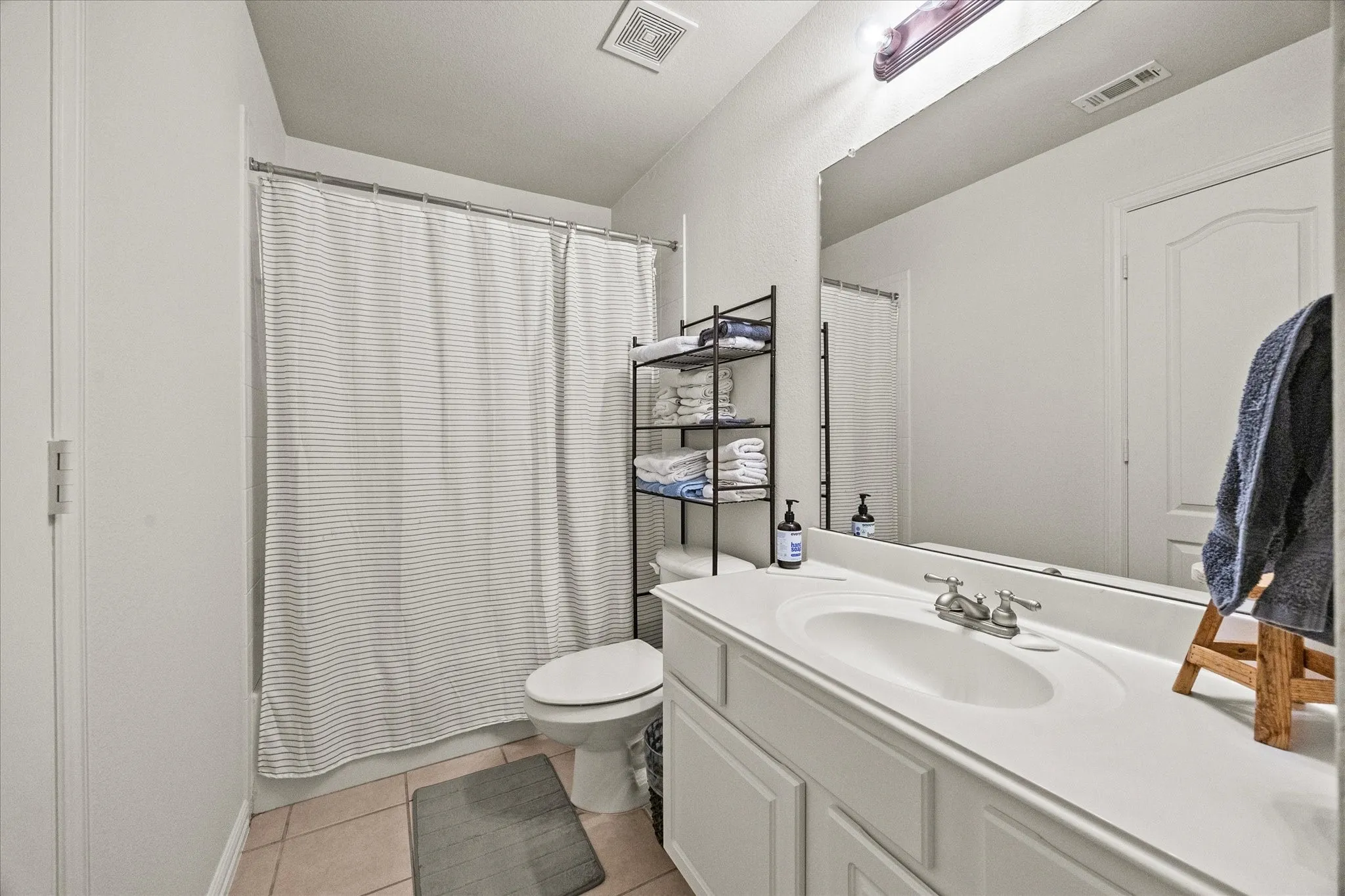 Bathroom featuring a single vanity with an integrated sink, polished chrome faucet, and a large wall-mounted mirror