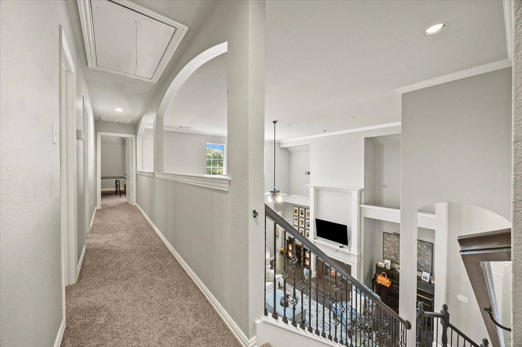 Carpeted hallway featuring arched openings, recessed lighting, and crown molding