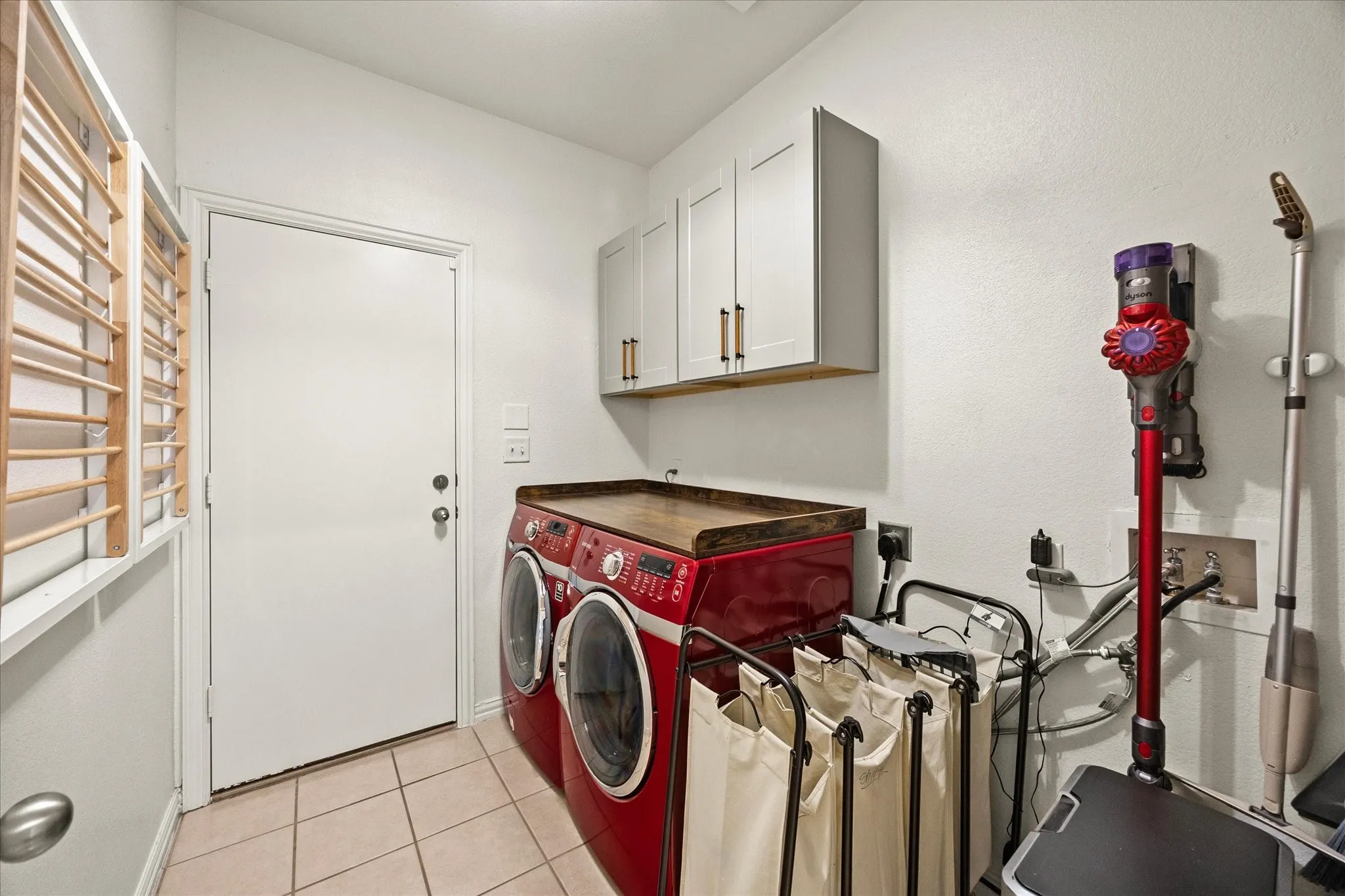 Laundry area with tiled flooring, white walls, and built-in upper cabinetry