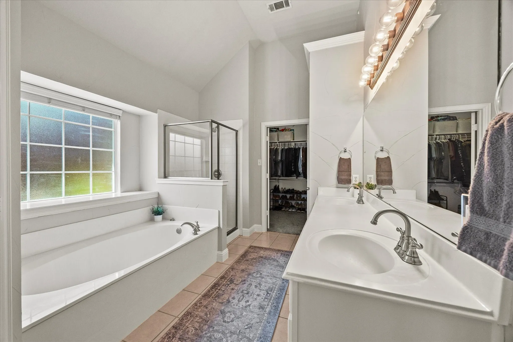 1602 Mapleleaf Drive Wylie, TX 75098 Built-in soaking tub with a large window, glass-enclosed shower, dual vanity with undermount sinks, and walk-in closets