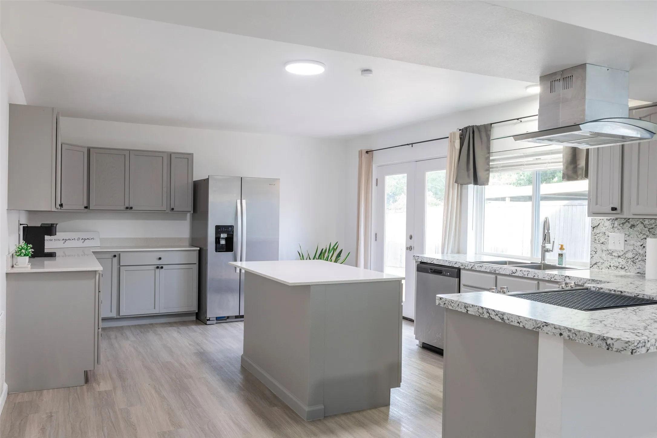 Kitchen featuring light gray cabinetry, stainless steel appliances, granite countertops, and wood-finish flooring