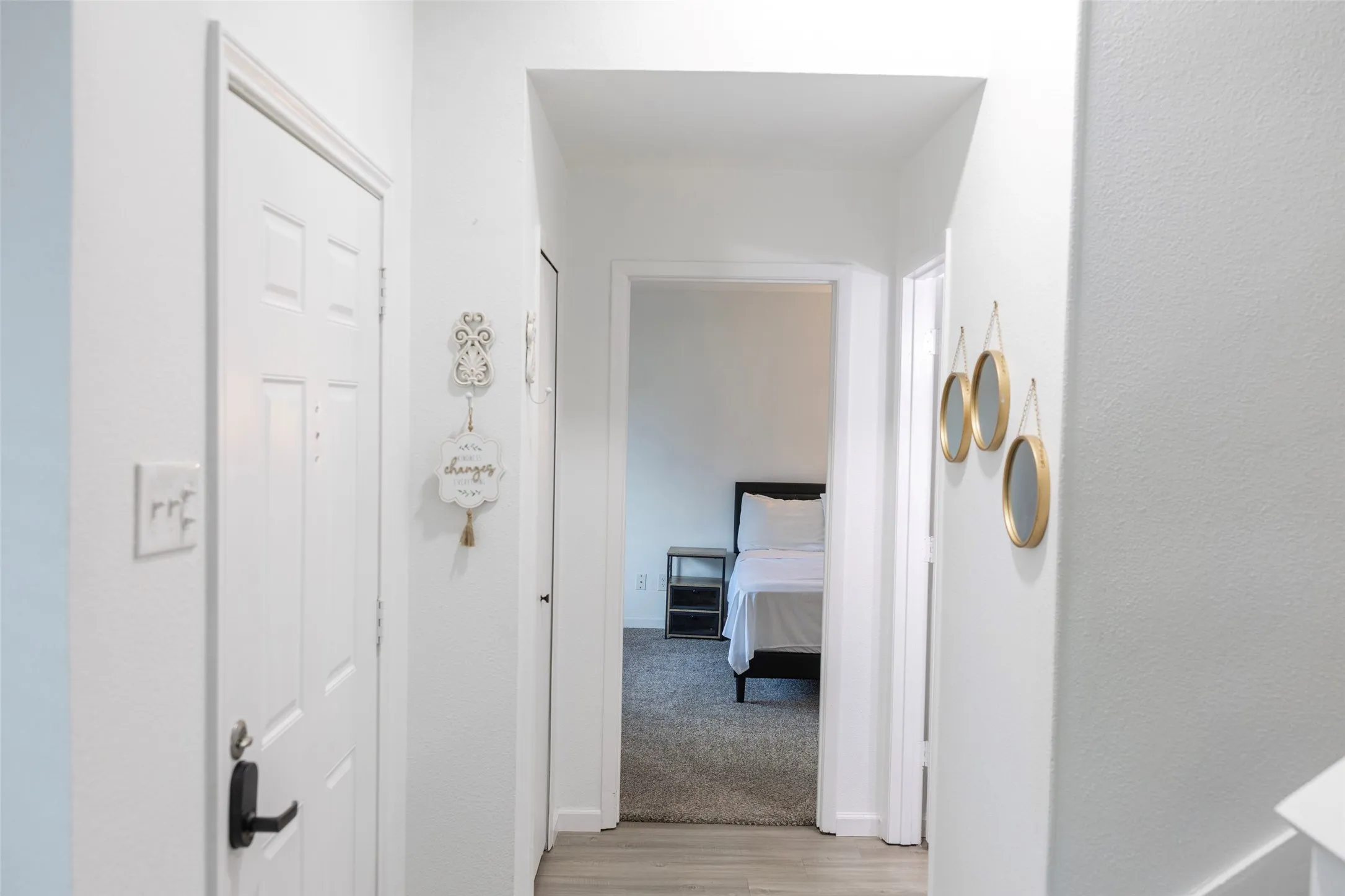 Hallway with light-colored flooring, white walls, and a white interior door with black hardware