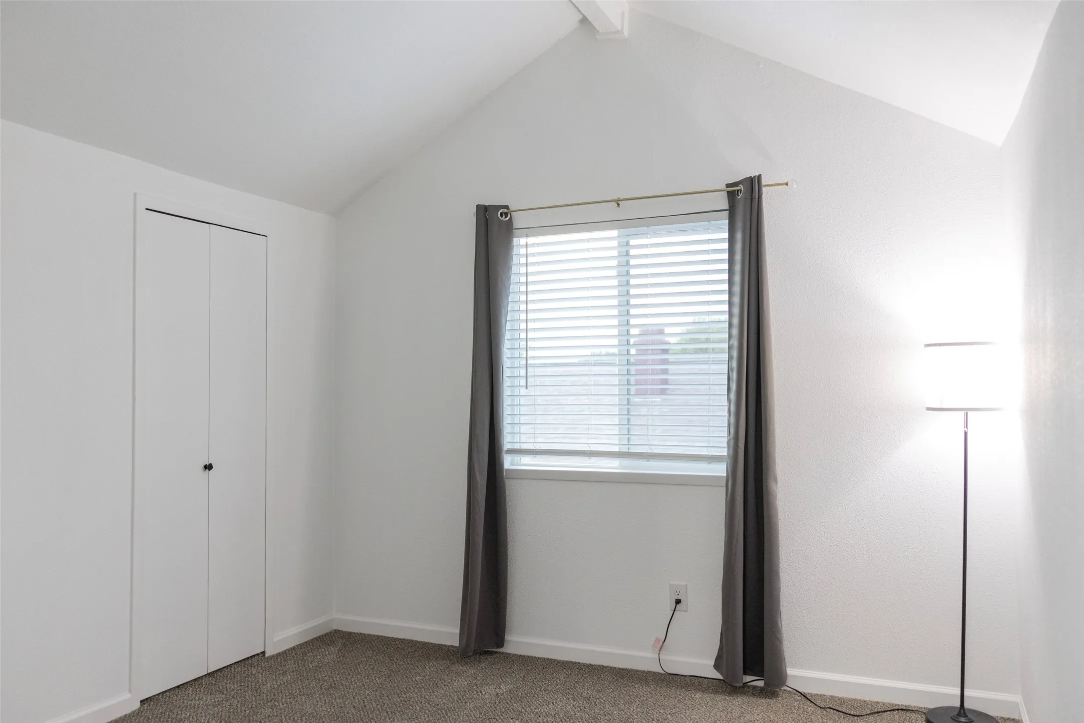 Vaulted ceiling, window with blinds, bi-fold closet, and carpeted flooring
