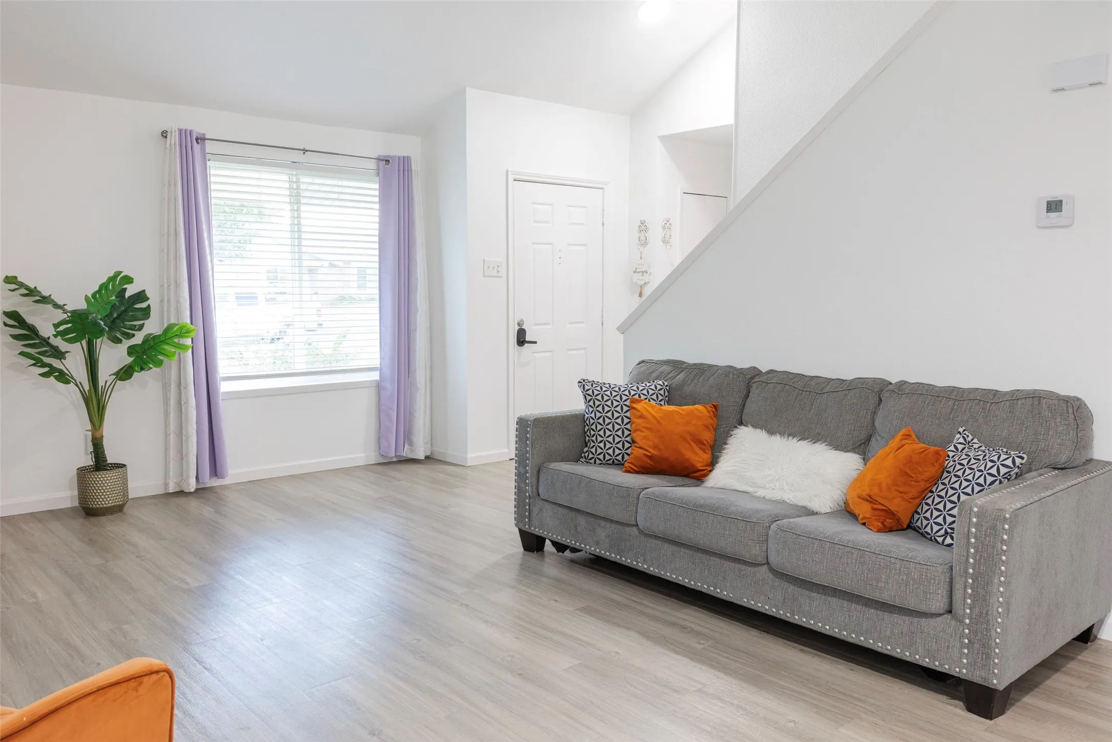 Recessed window with blinds, wood-finish flooring, white walls, and a white paneled door