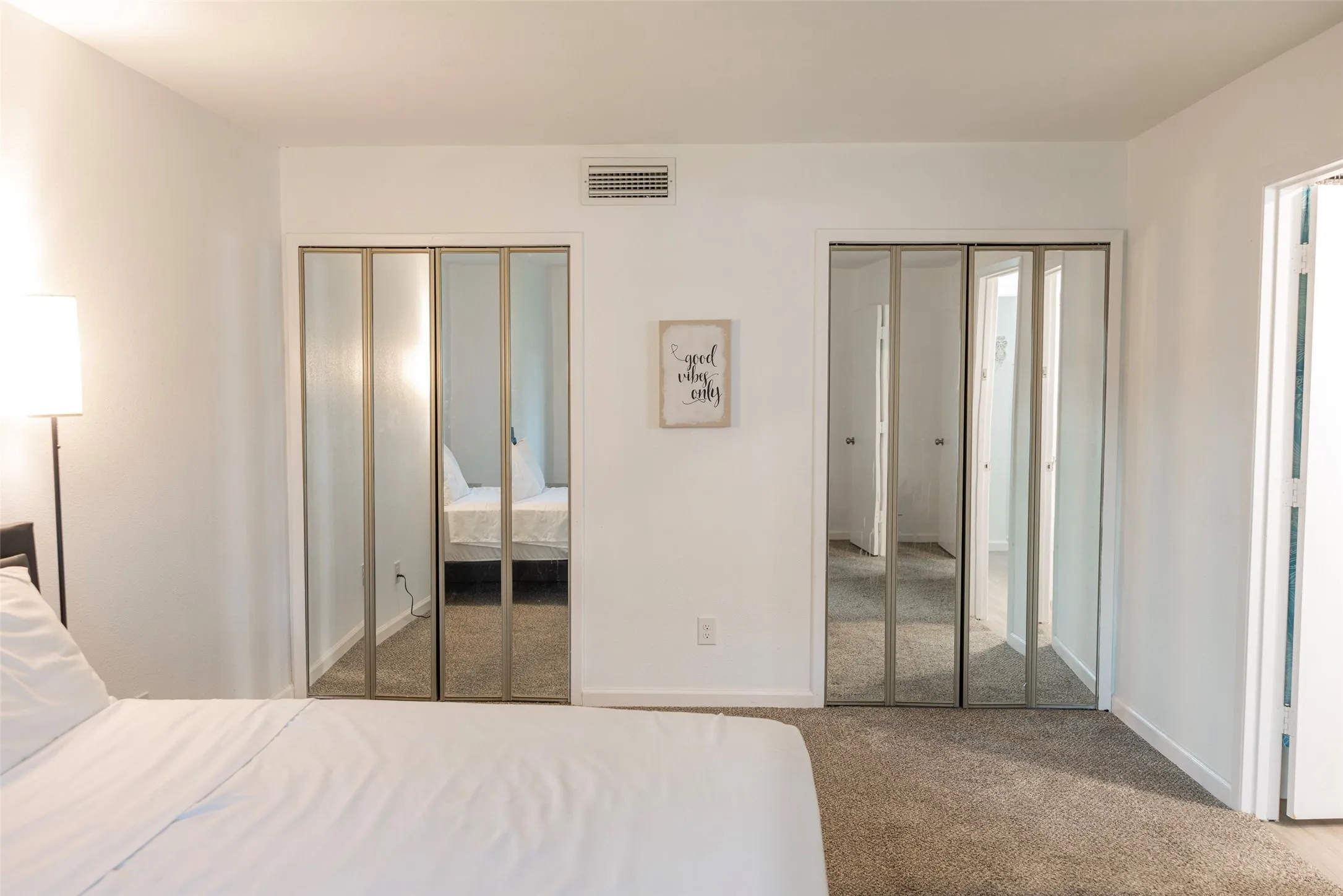 White walls, gray carpet, mirrored bi-fold closet doors, and white trim