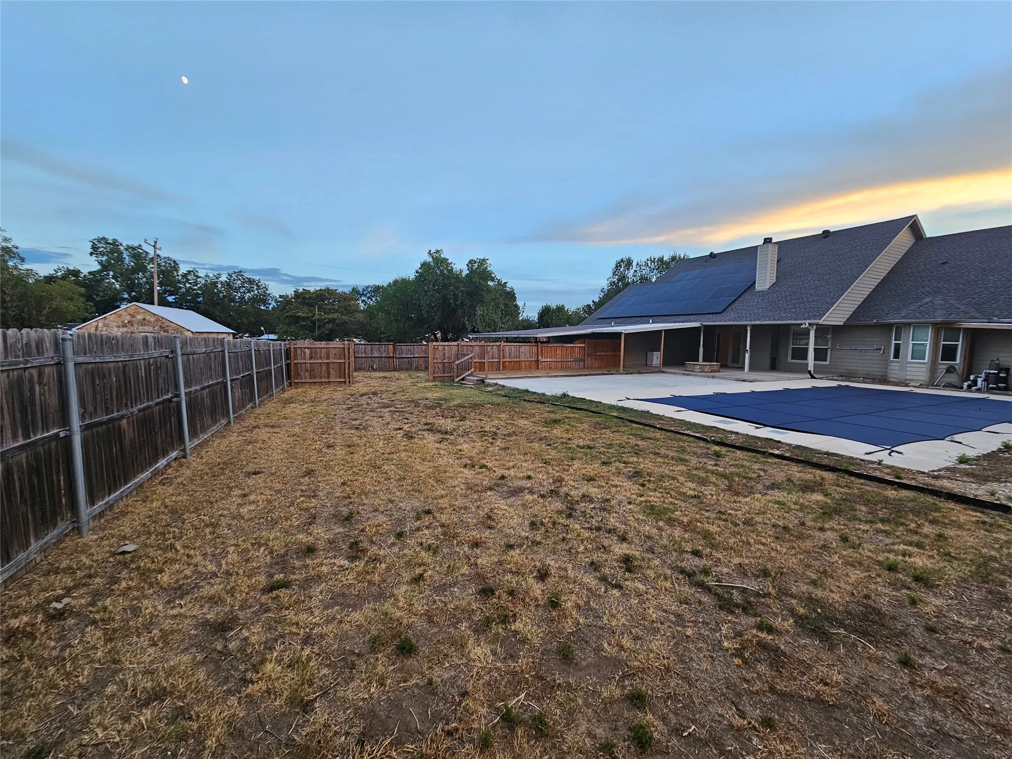Expansive backyard featuring a privacy fence, concrete patio, and in-ground pool