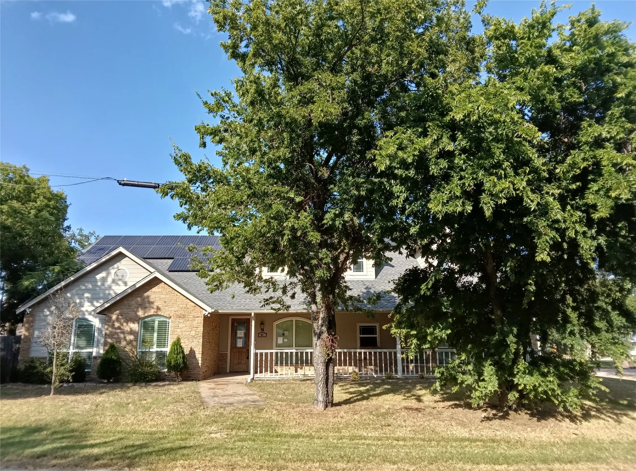 Brick and siding exterior with a covered front porch, solar panels, and arched windows