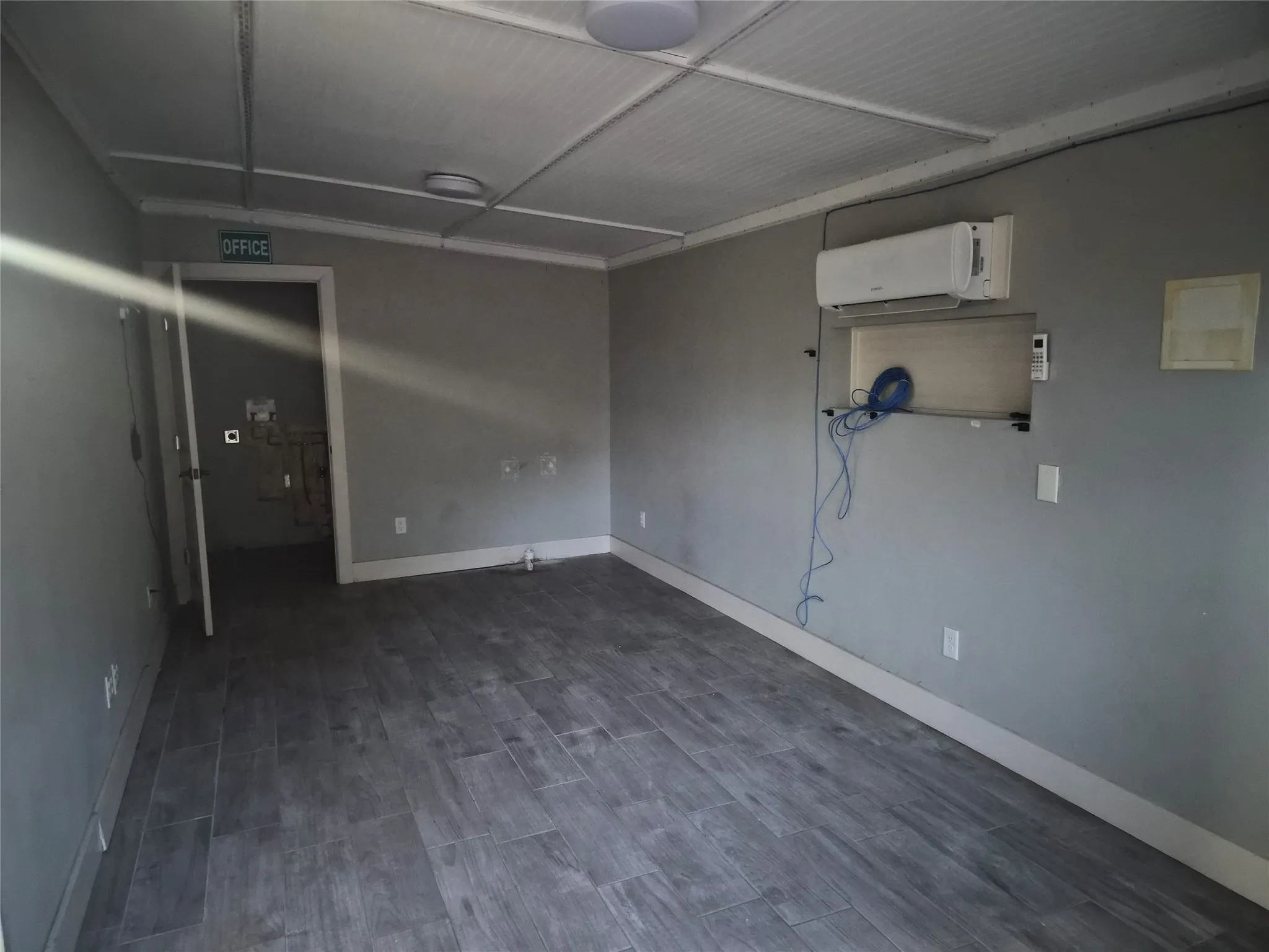 Wood-look tile flooring, light gray wall finishes, and a ceiling-mounted light fixture