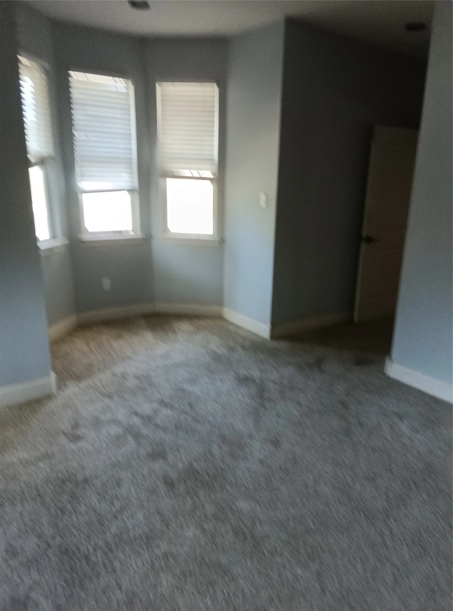 Bay window with multiple window treatments and light gray walls