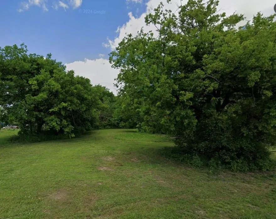 Expansive green space featuring a large grassy area and mature trees