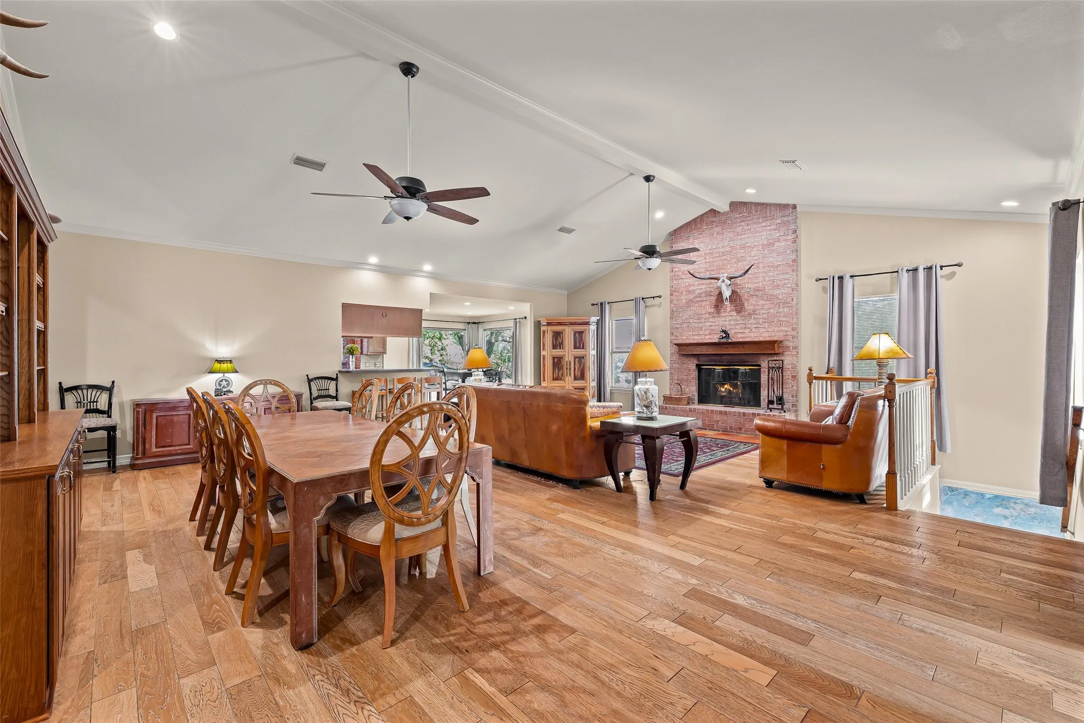 Vaulted ceiling, wood-finish flooring, brick fireplace, built-in shelving, and recessed lighting