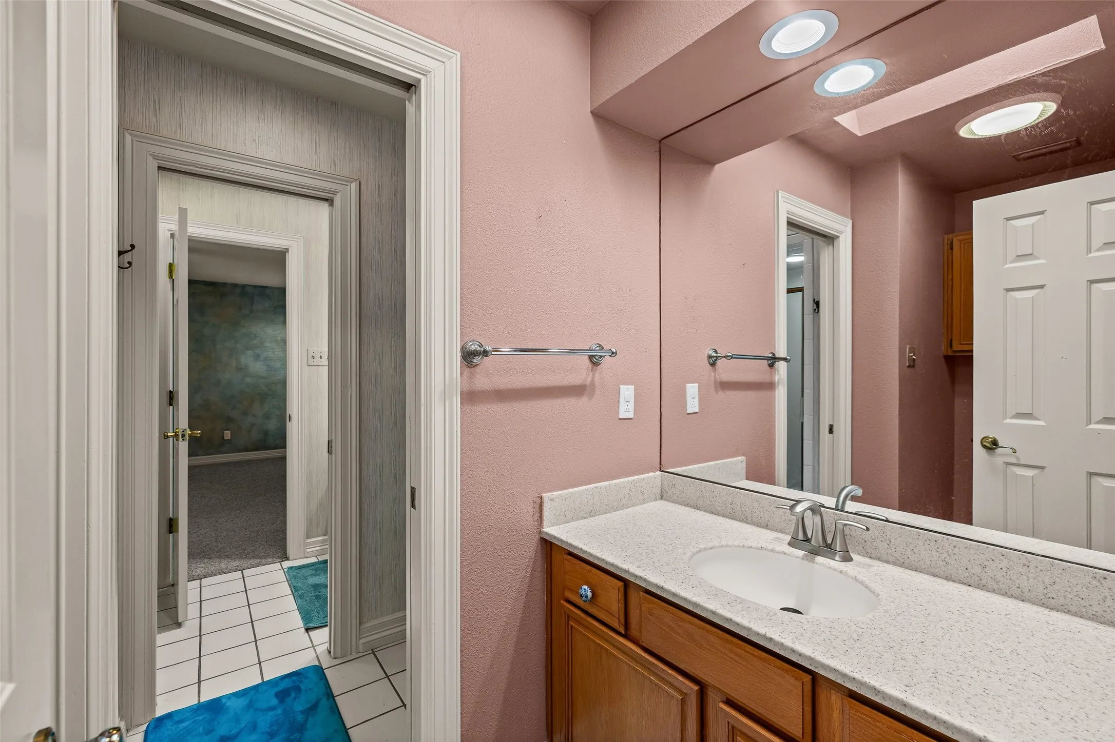 Vanity with a light-toned countertop, undermount sink, and wood-finish cabinetry