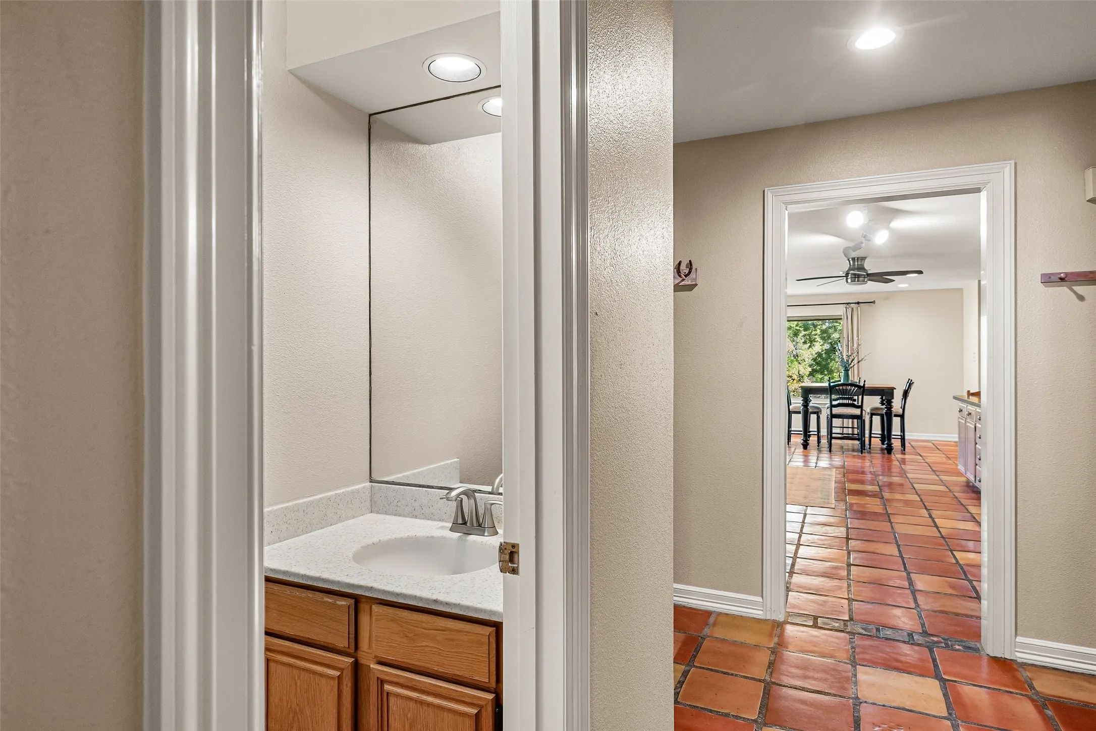 Powder room with a wood-finish vanity and integrated sink, complemented by a large wall mirror