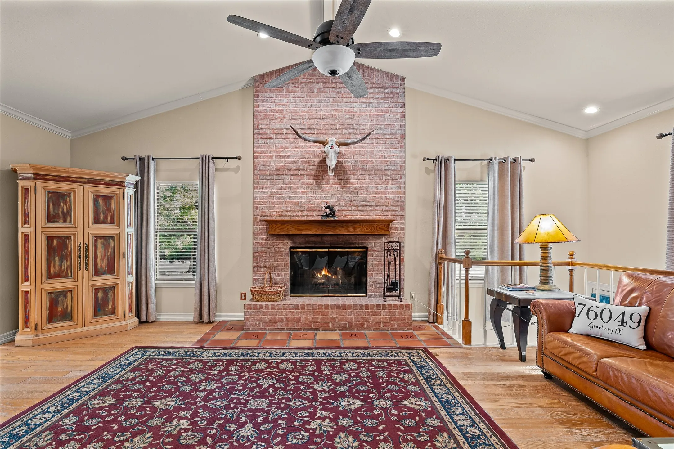 Brick-faced fireplace with a wood mantle, vaulted ceiling, and wood-finish flooring