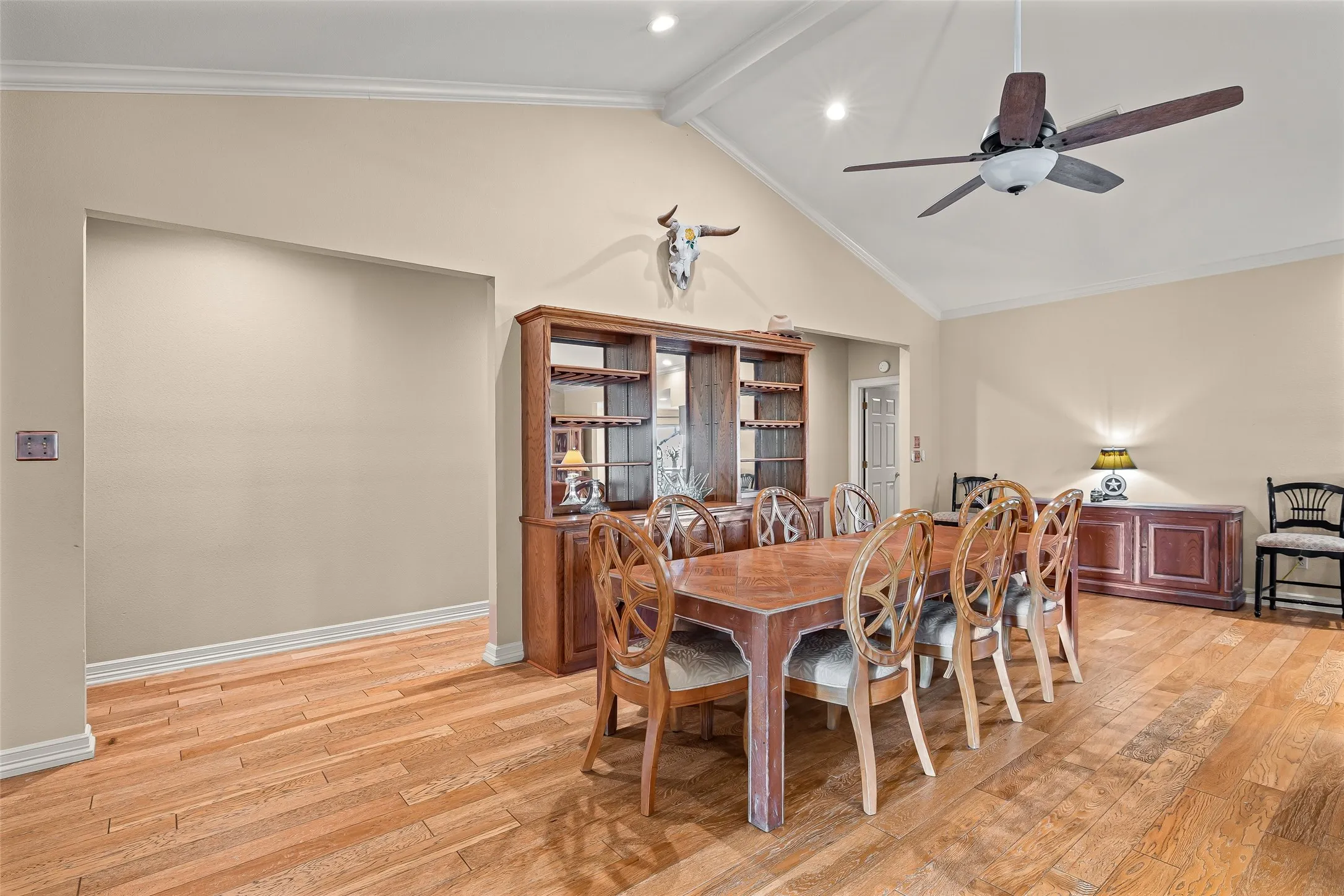 Vaulted ceiling with crown molding, natural wood-finish flooring, recessed lighting, and a prominent ceiling fan