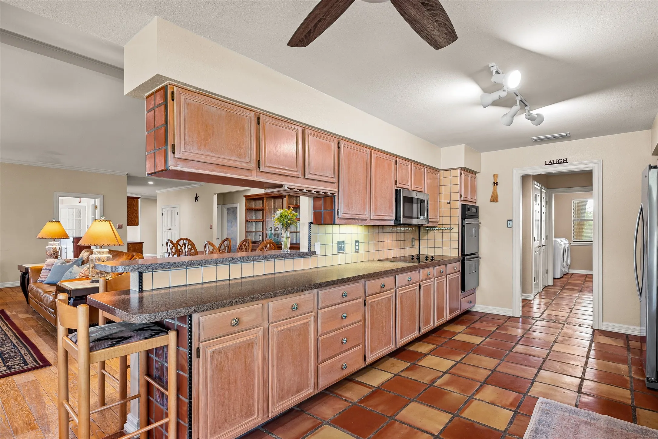 Kitchen featuring tile flooring, wood cabinetry, built-in double oven, and a tile backsplash