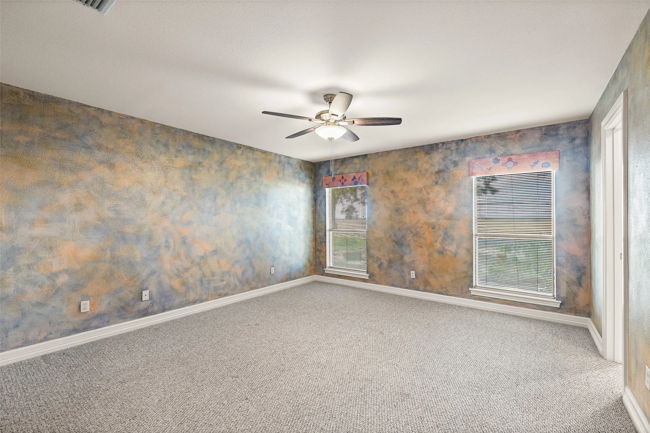 Recessed ceiling fan, textured wall finish, two large windows with blinds, and light-colored carpeting