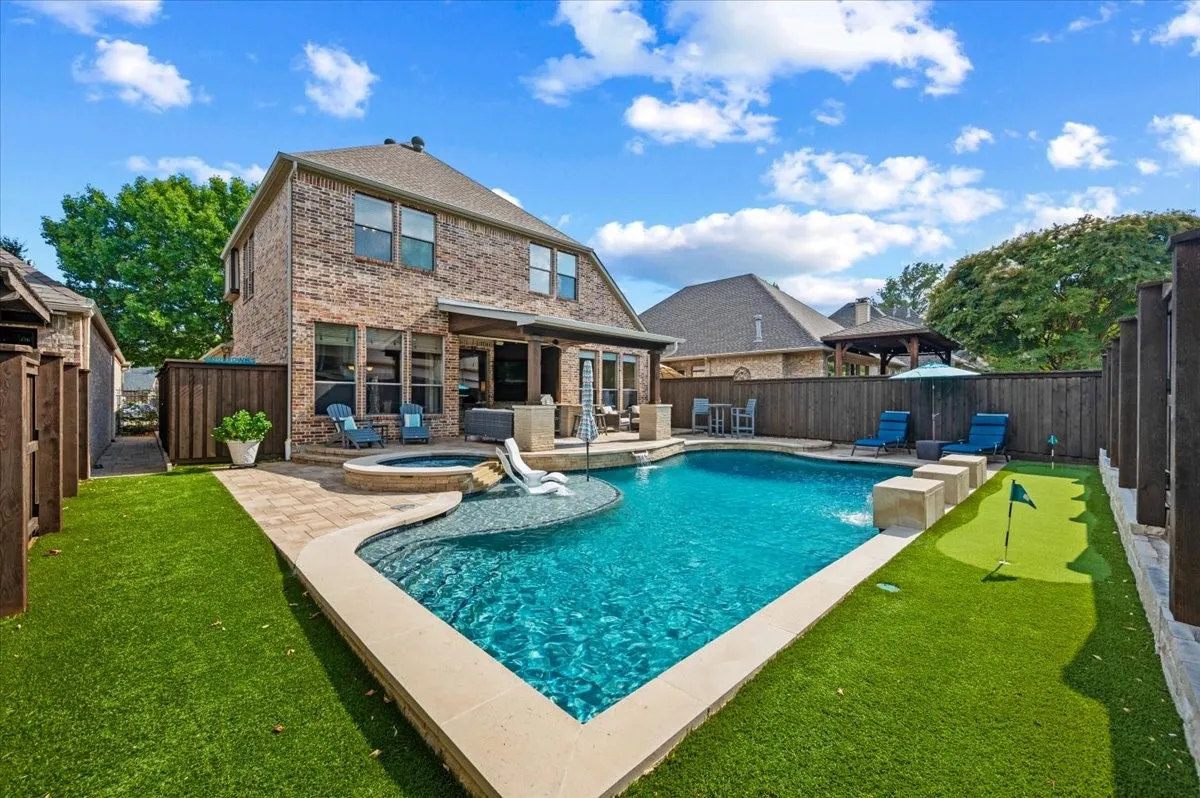 Sparkling pool, spa, putting green, outdoor kitchen, multiple dining and lounging areas.