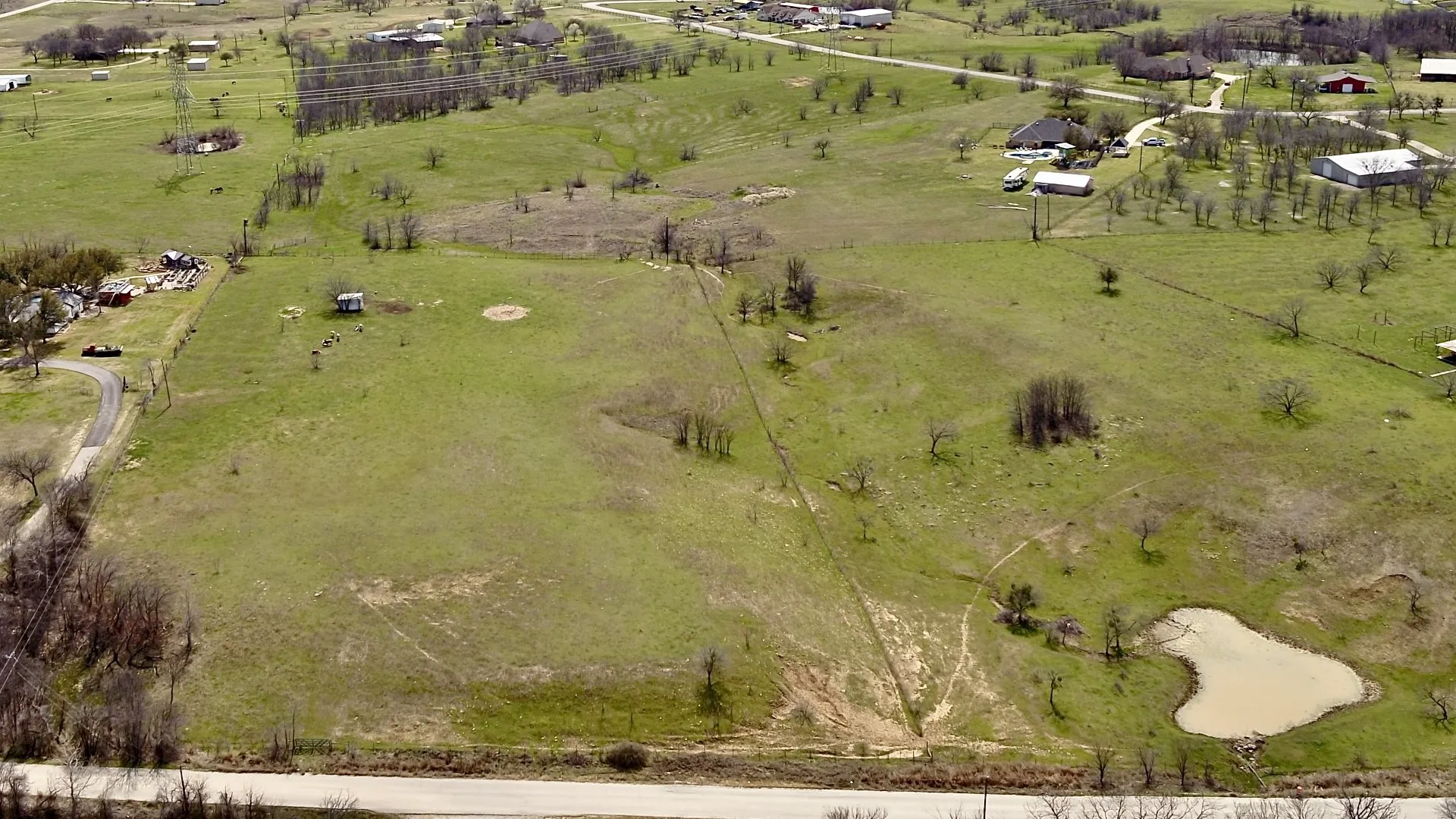 Expansive land parcel featuring a natural pond, scattered trees, and visible clearings