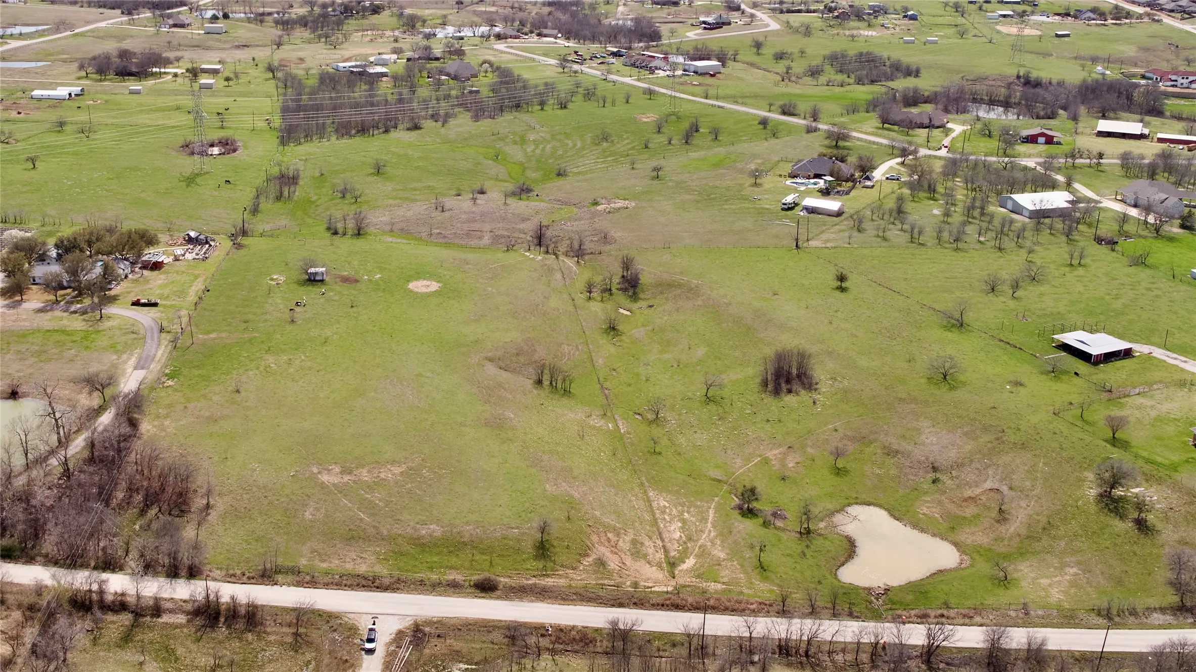 Expansive open terrain with a natural pond and established trees
