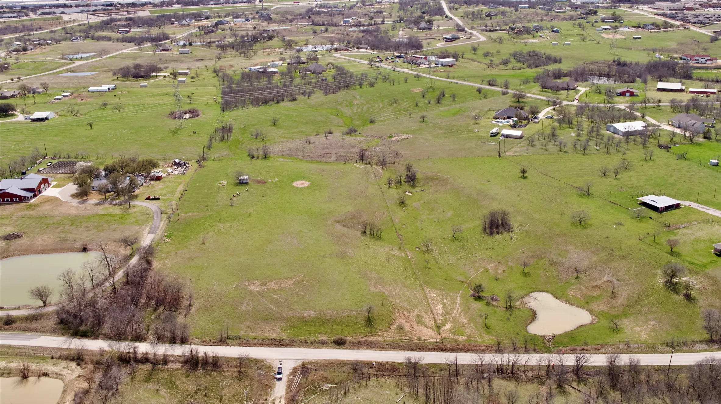 Expansive land parcel featuring a main road frontage, two visible ponds, and varied topography with scattered trees