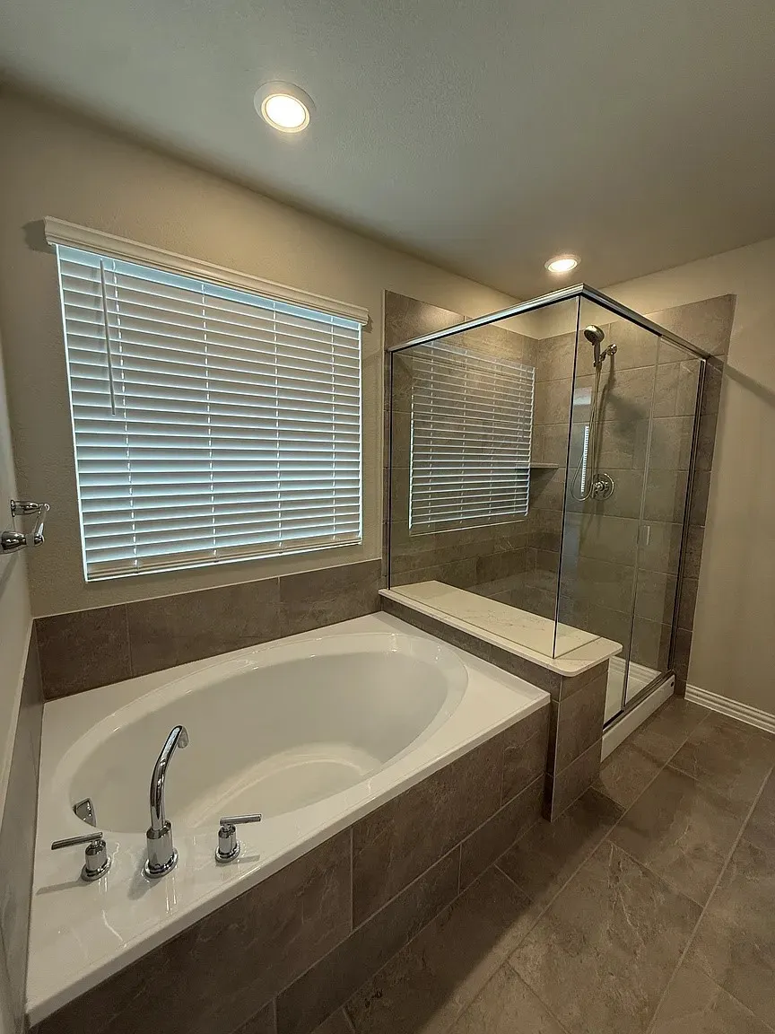 Bathroom featuring a built-in soaking tub with chrome fixtures, a glass-enclosed shower with a built-in bench, and recessed lighting