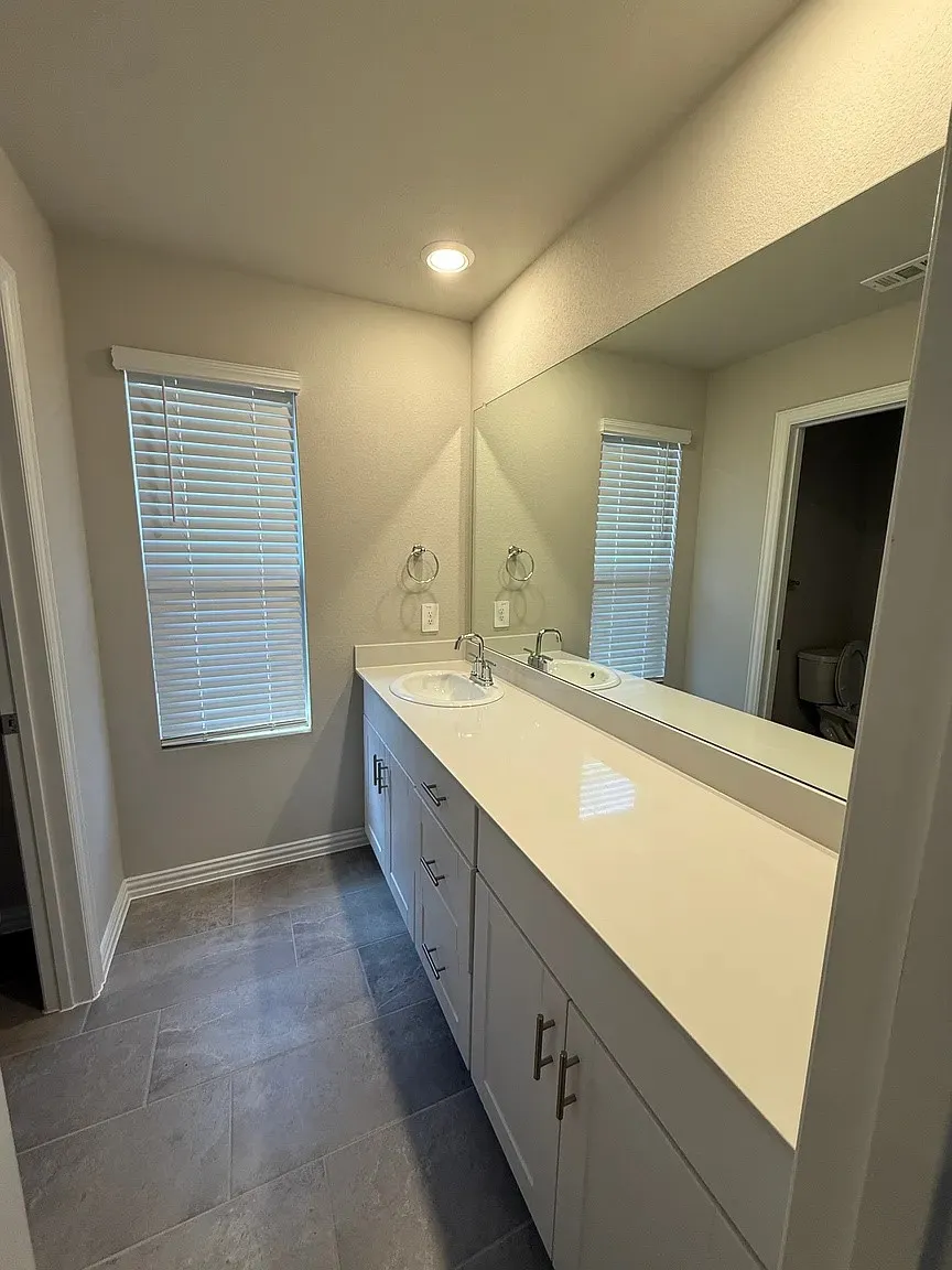 Double vanity with undermount sinks, stone countertops, and ample storage cabinetry
