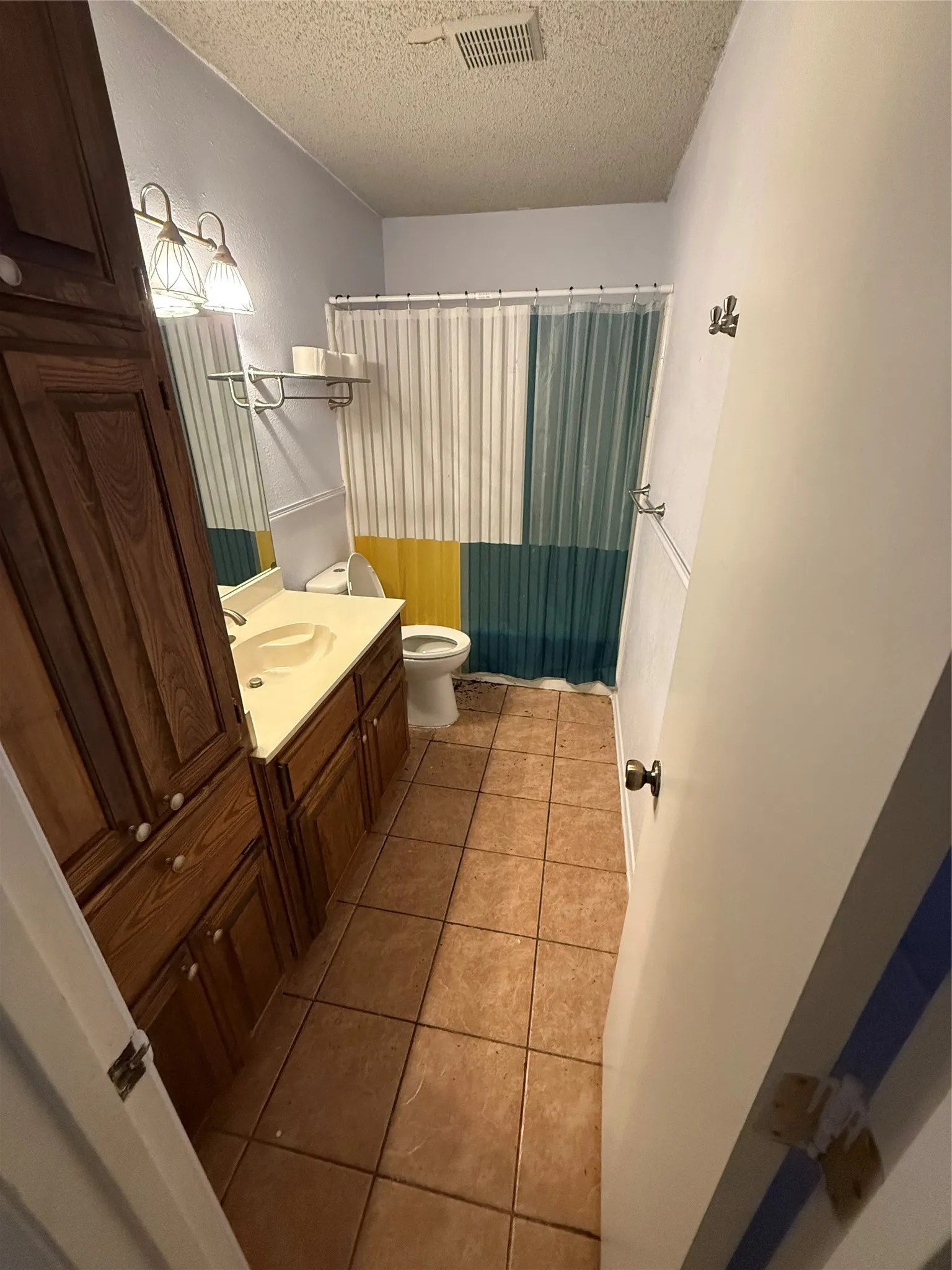Built-in wood cabinetry, integrated vanity with a single sink, tiled flooring, and wall-mounted lighting