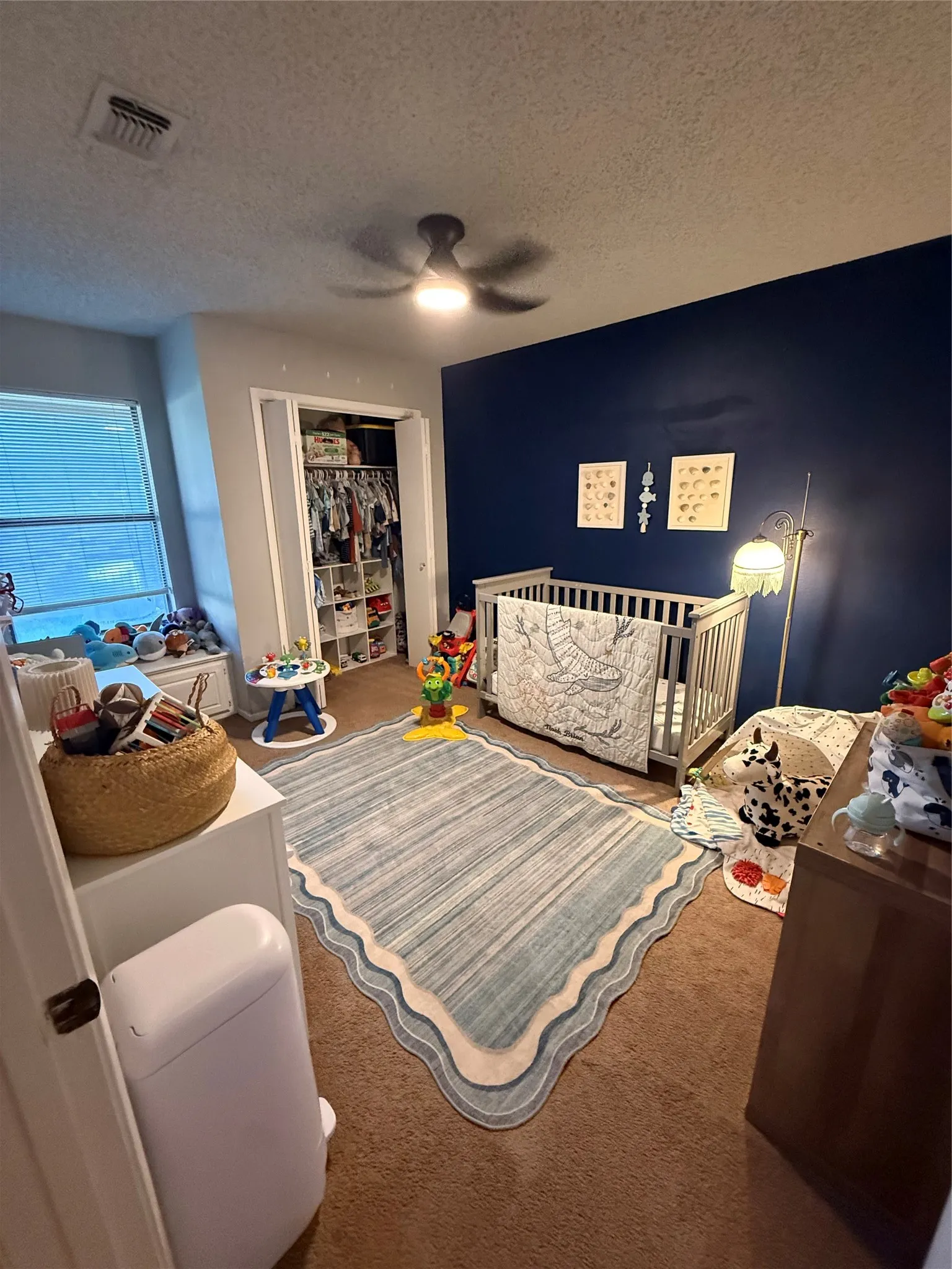 Recessed window with blinds, ceiling fan with integrated lighting, built-in closet with shelving, and carpeted flooring
