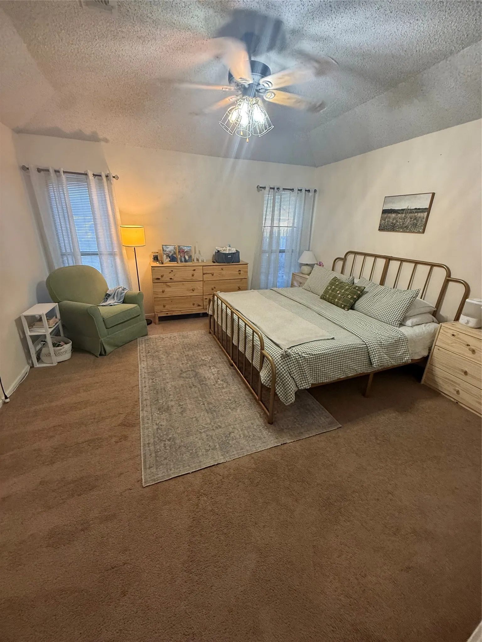 Vaulted ceiling with an attached ceiling fan, two windows with blinds, and wall-to-wall carpeting