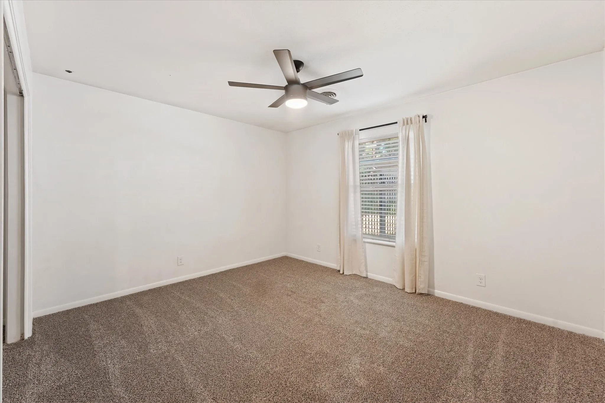 Neutral wall paint, new plush carpeting, ceiling fan with integrated lighting, window with blinds