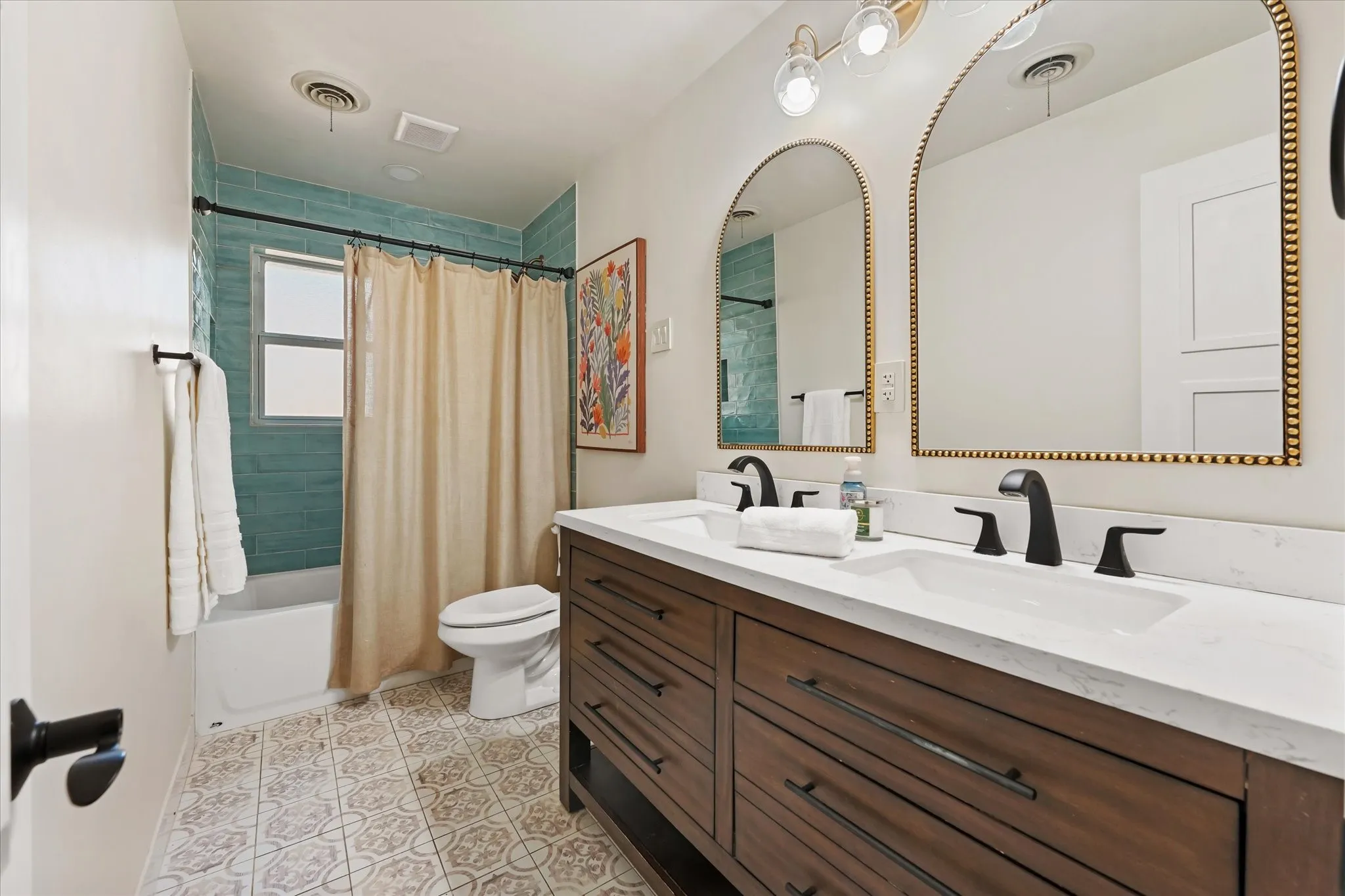 Dual vanity with wood-finish cabinetry, quartz countertop, and matte black fixtures