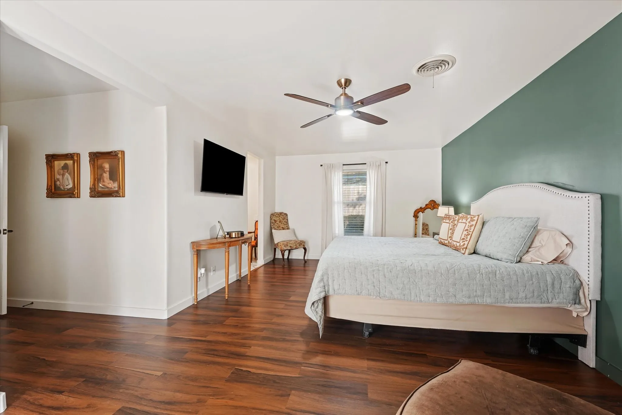 Wood-finish flooring throughout, ceiling fan with integrated lighting, and a window with white window coverings