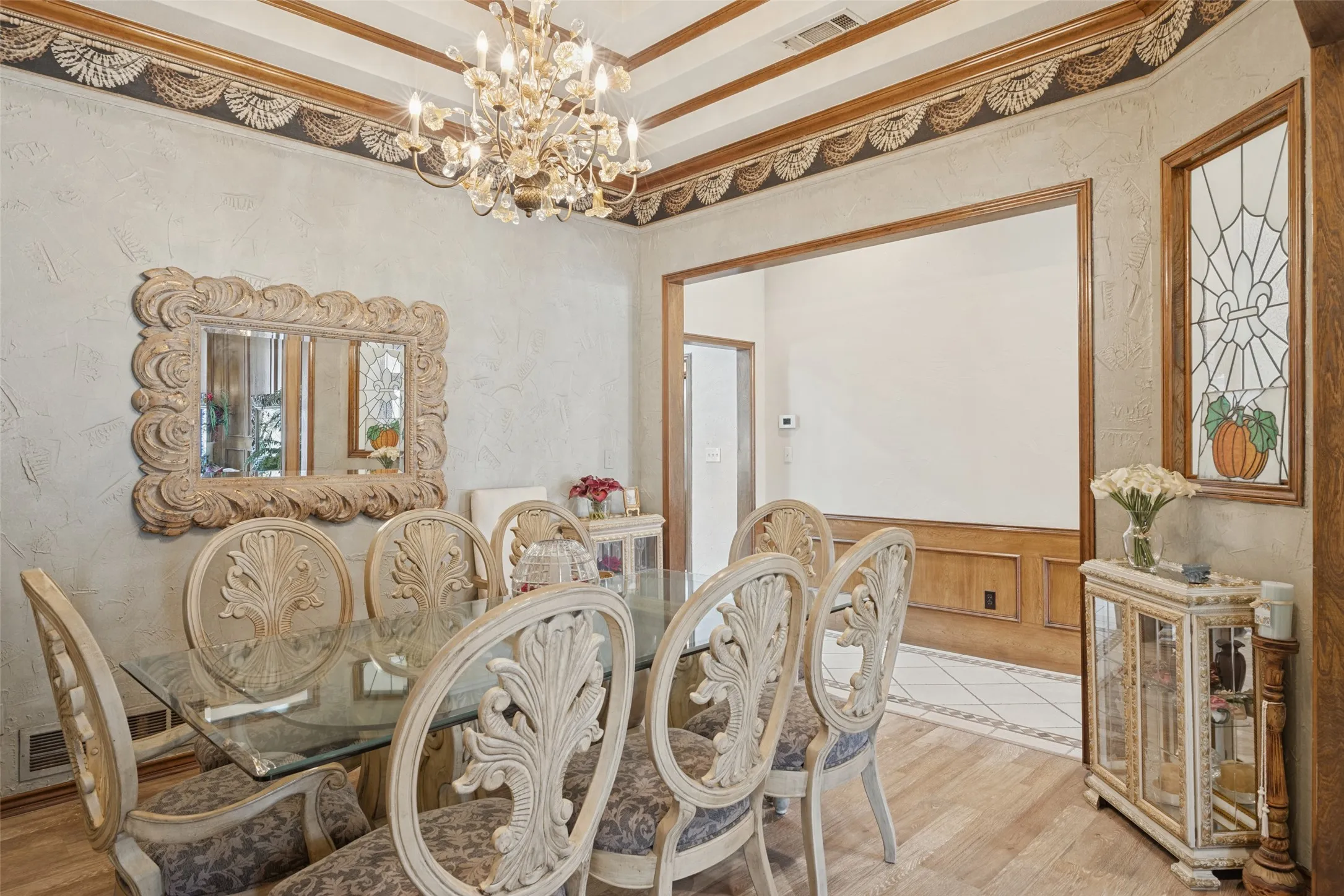 Wood-finish flooring, coffered ceiling with decorative molding, and a chandelier