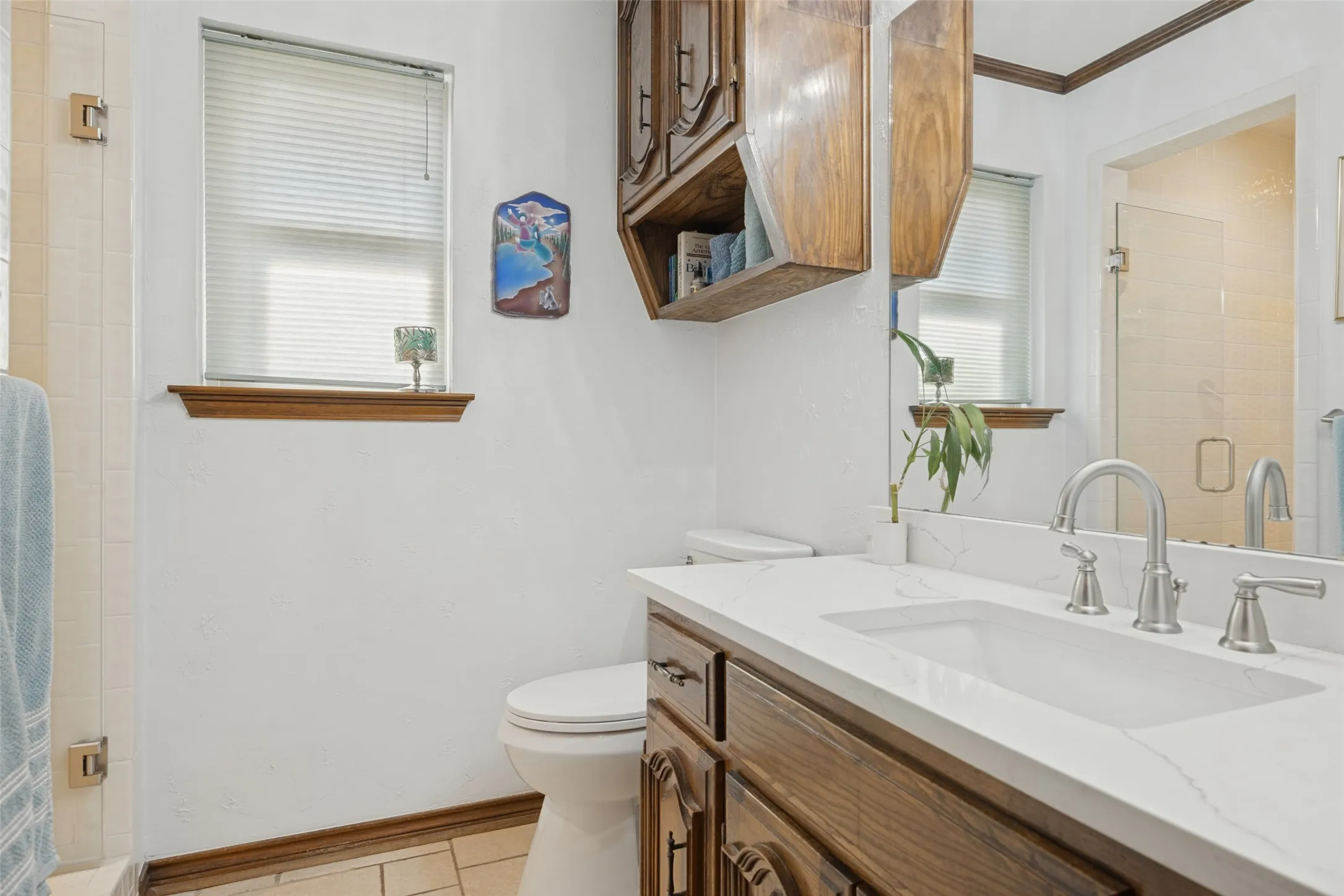 Bathroom featuring a single vanity with wood-finish cabinetry, a white countertop, and a rectangular undermount sink