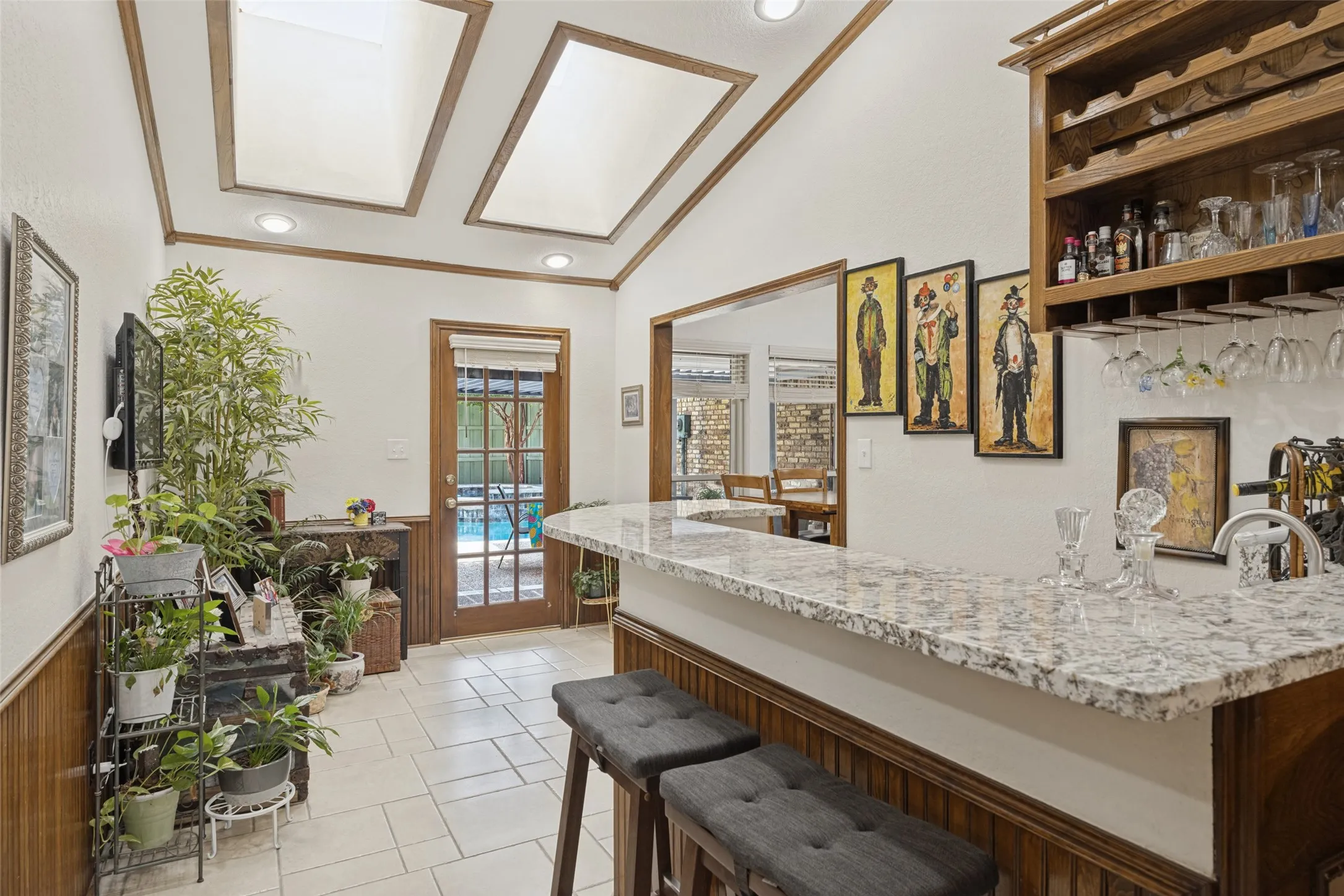 Vaulted ceiling with skylights and recessed lighting, wet bar with granite-finish countertop, built-in wine rack