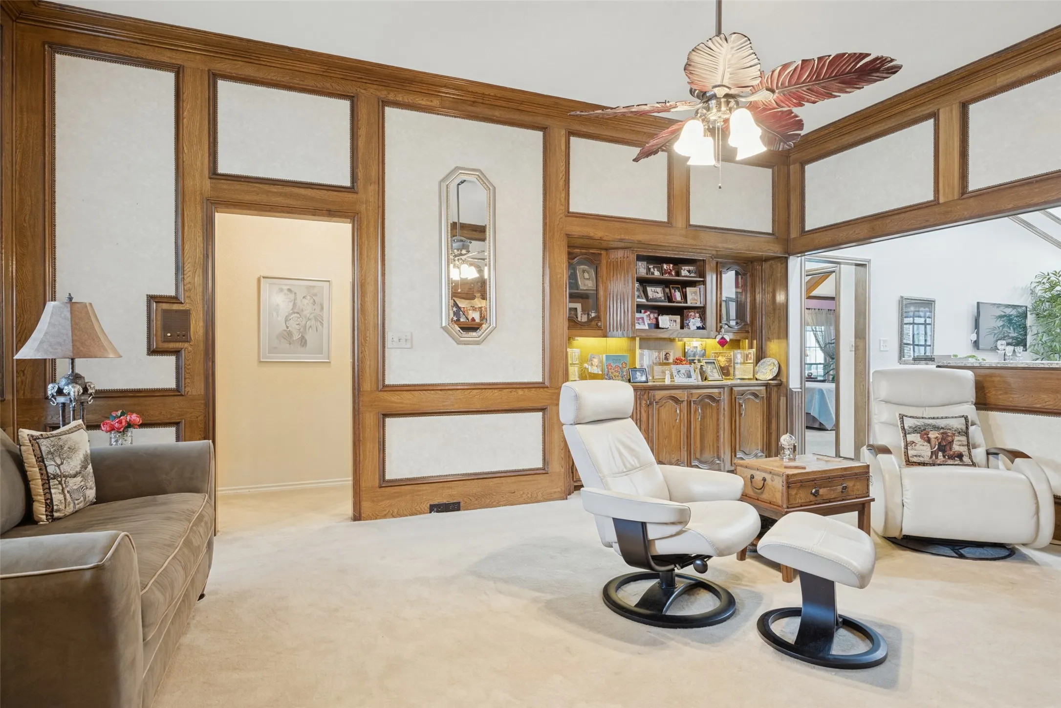 Paneled walls with wood trim, built-in cabinetry, and a ceiling fan with integrated lighting