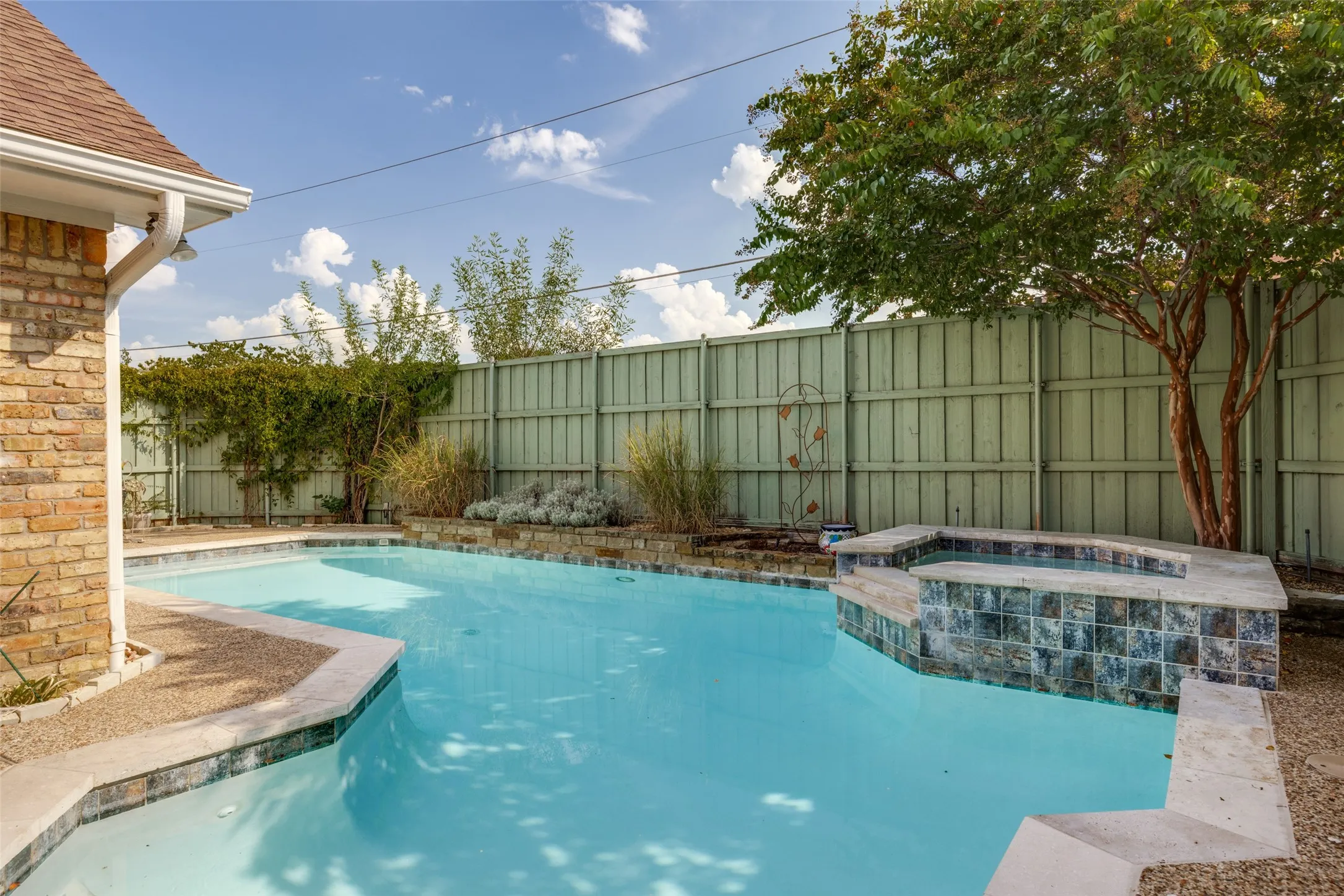 Backyard featuring a swimming pool, integrated spa with tile surround, and brick exterior