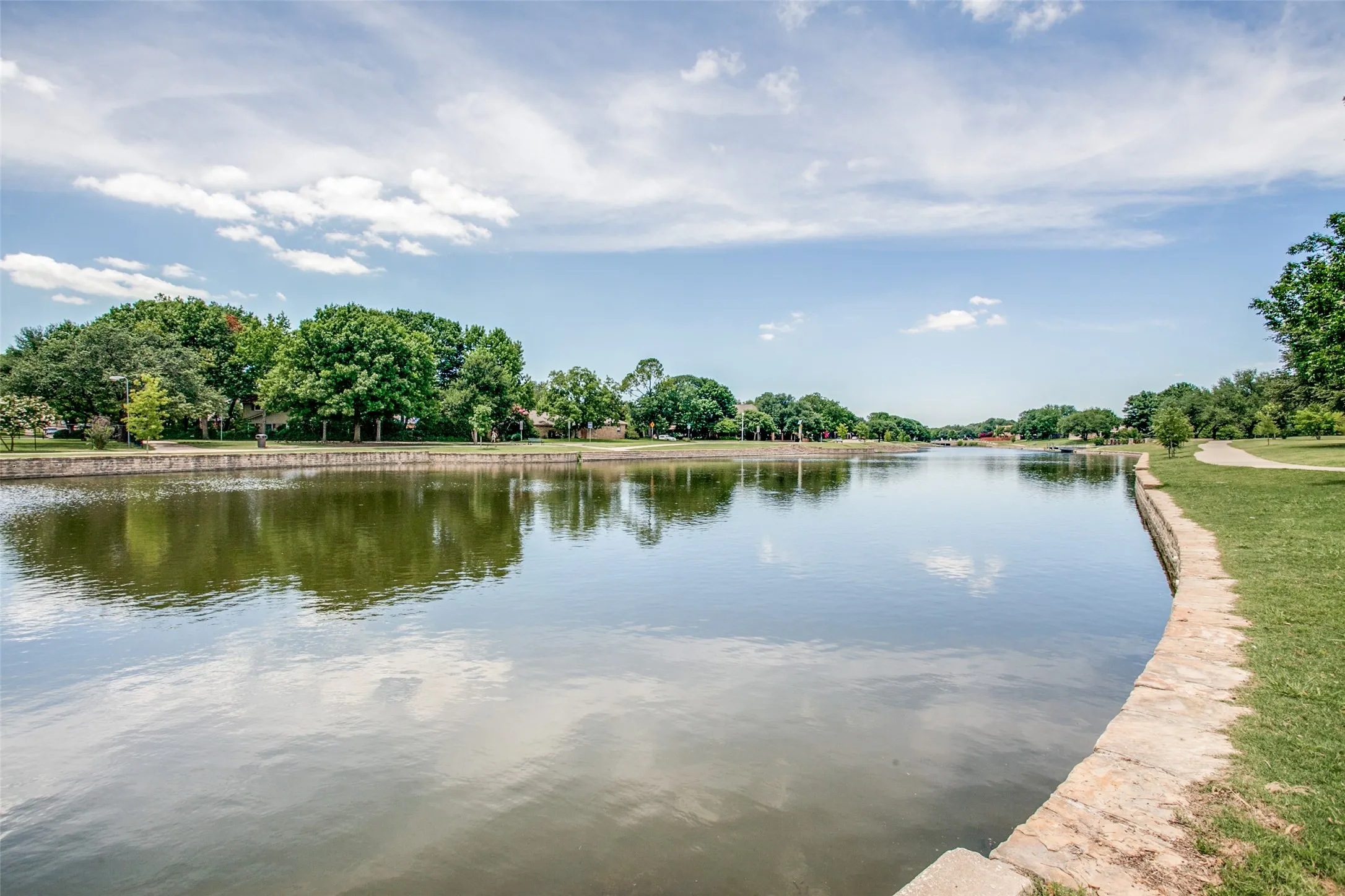 Waterfront property featuring a stone-lined bank, expansive water body, and mature trees