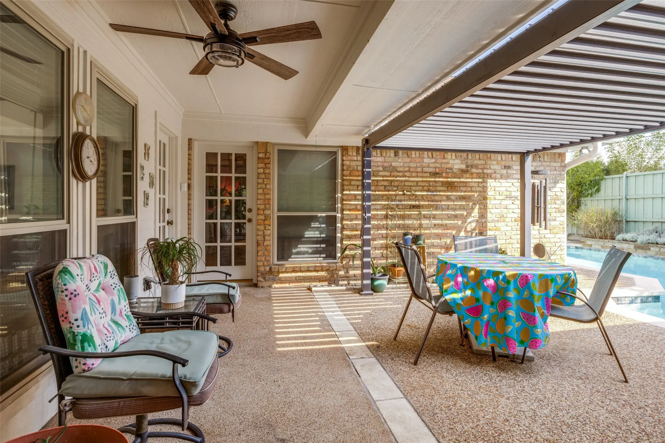 Expansive outdoor living area featuring a covered patio, exposed aggregate flooring, and a ceiling fan