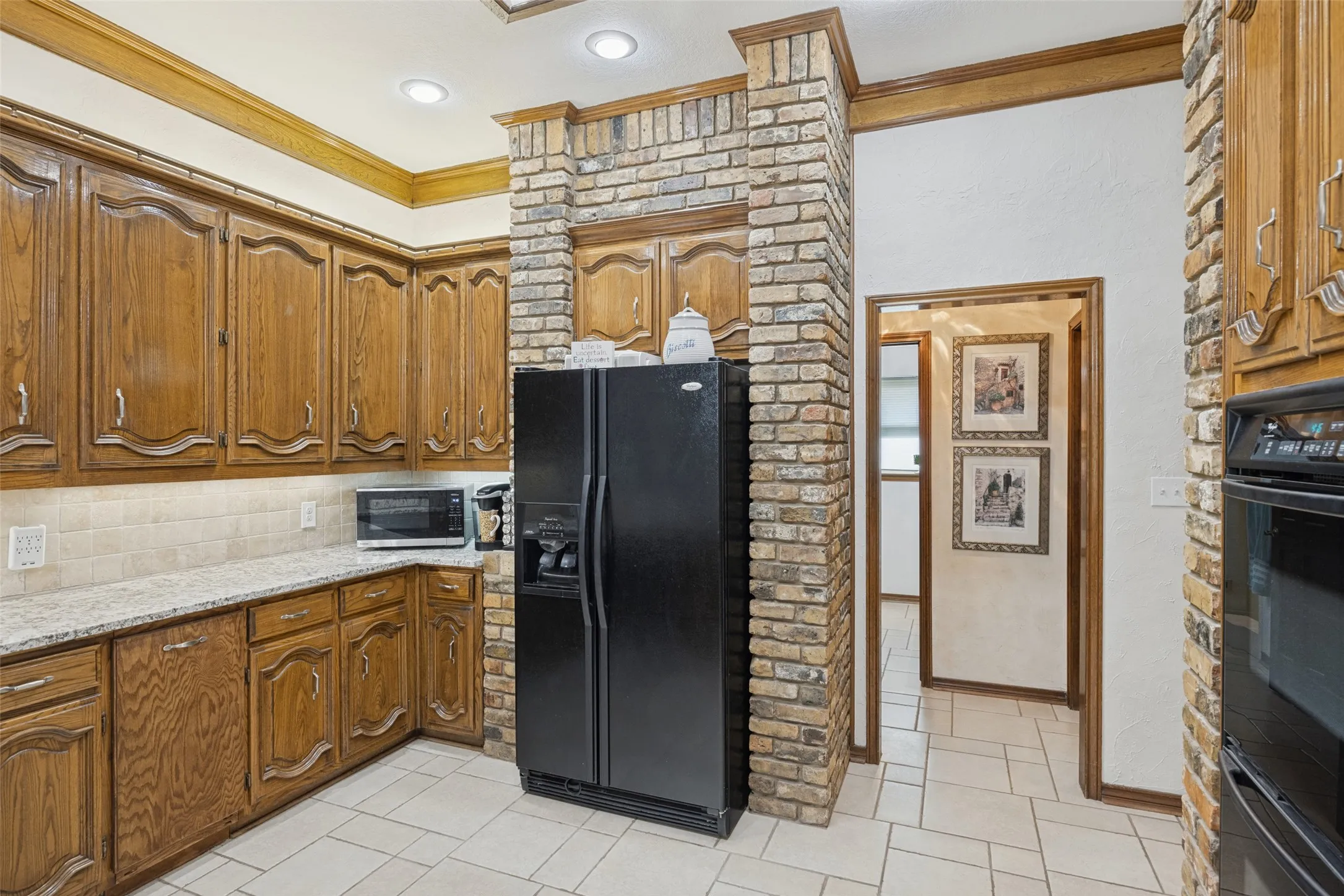 Kitchen featuring wood cabinetry, granite countertops, neutral tile backsplash, and recessed lighting