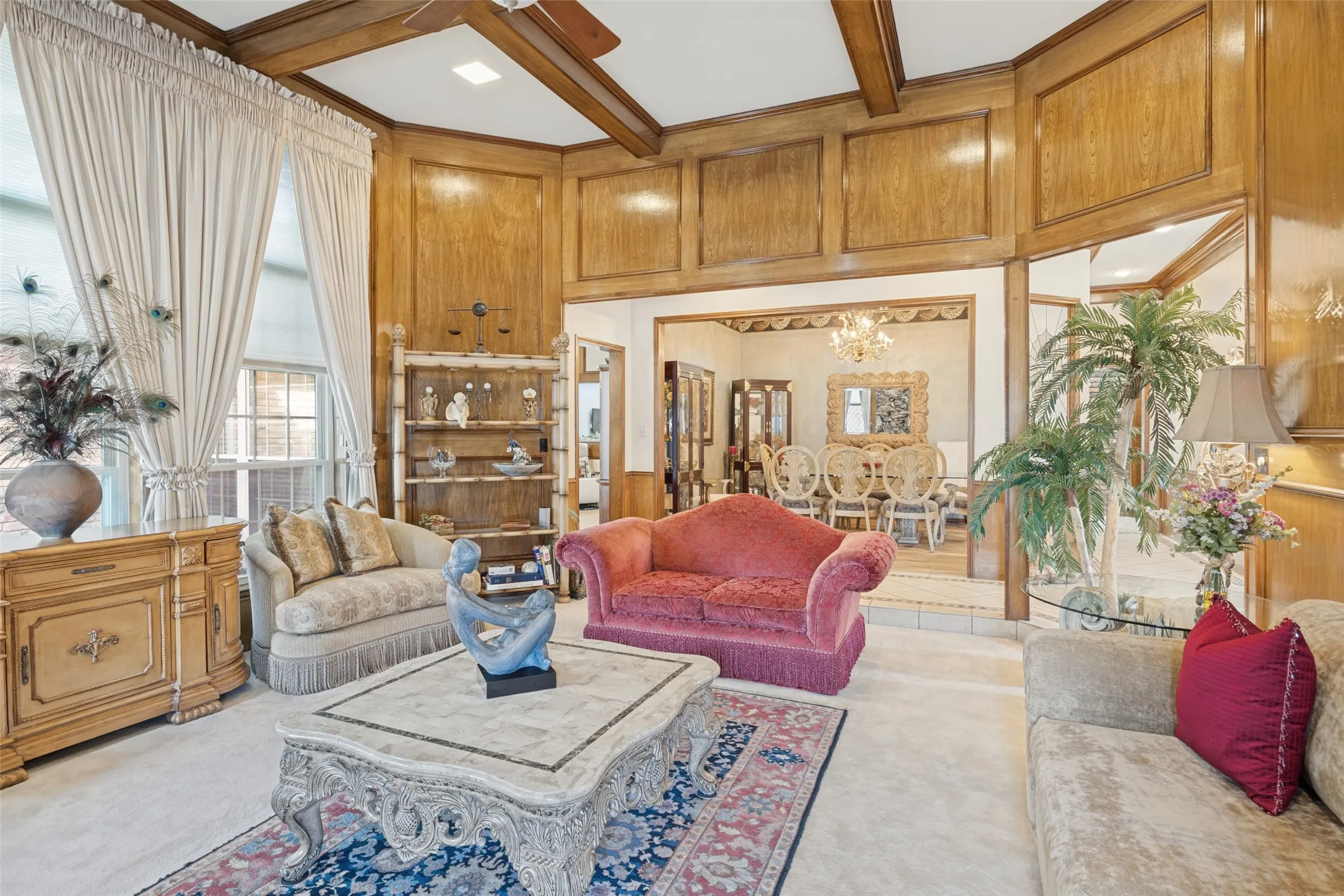 Wood-paneled walls and ceiling beams, large windows with full-length drapes