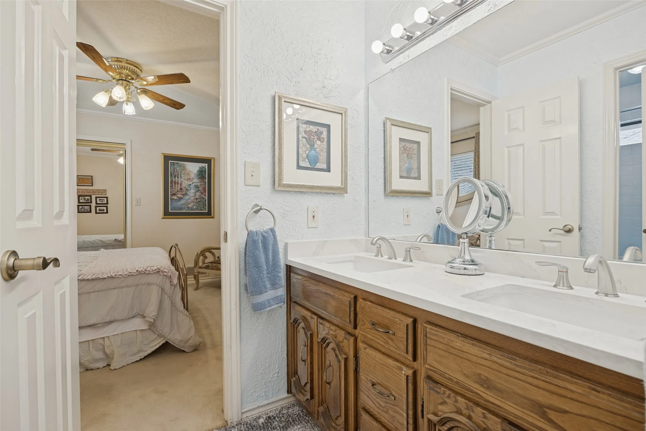 Double vanity with integrated sinks, white countertop, and wood-finish cabinetry