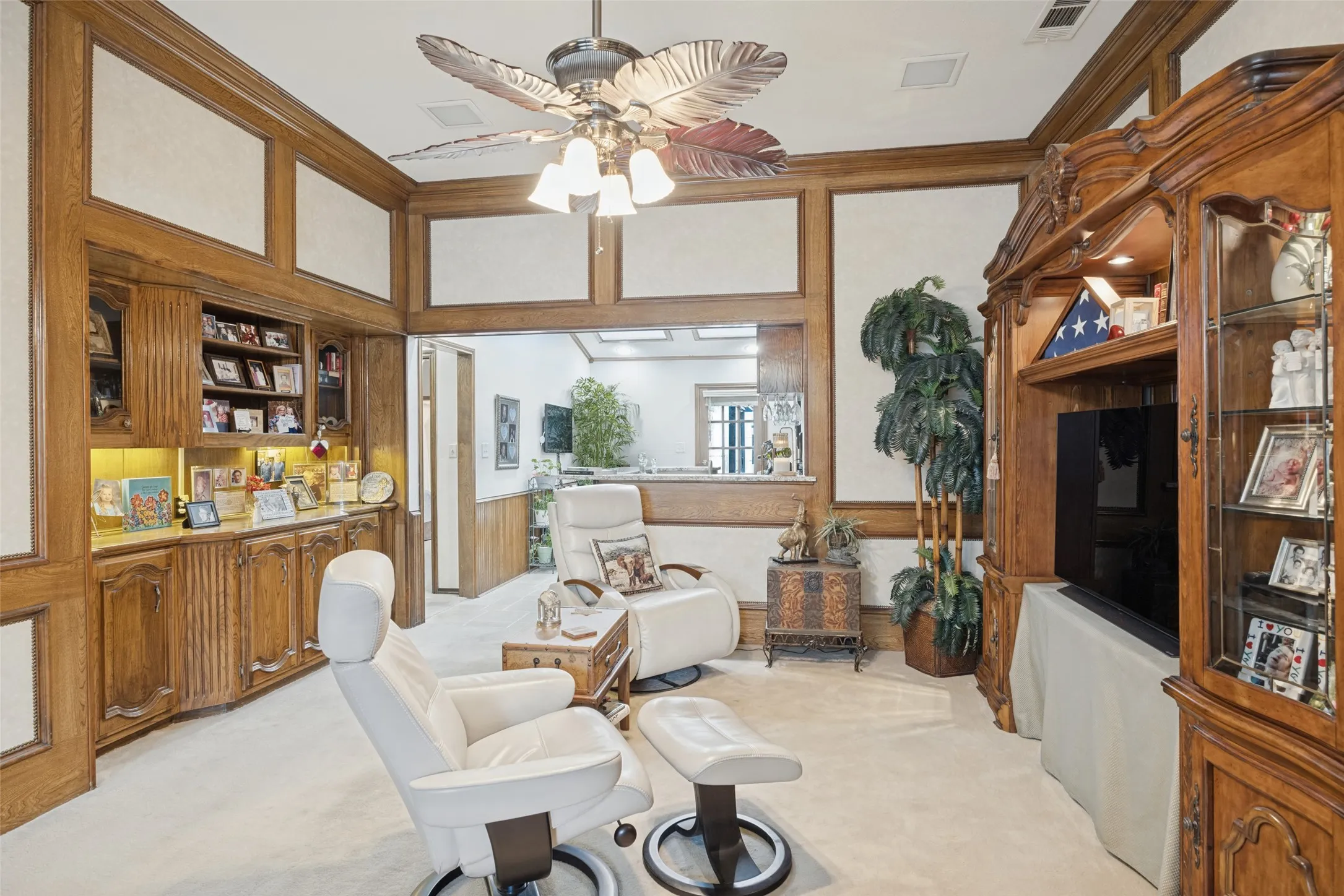 Wood-paneled walls with integrated display shelving, built-in cabinetry, and a ceiling fan with decorative blades