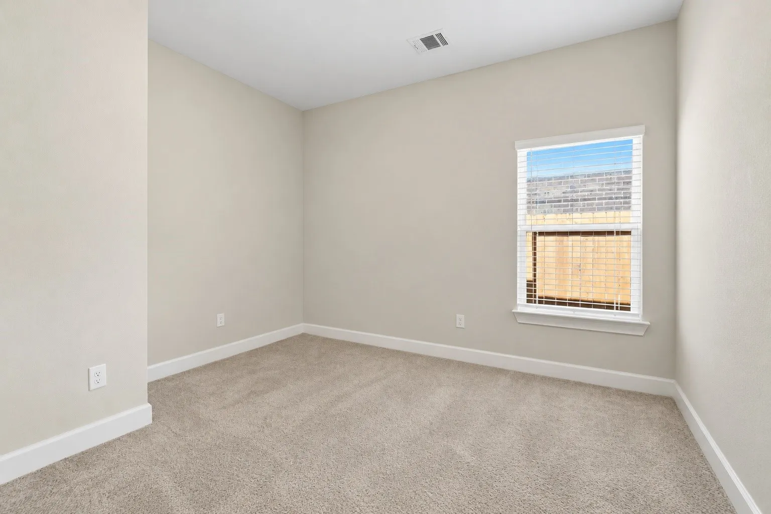 Neutral wall paint with carpet flooring, white trim, and a window with blinds