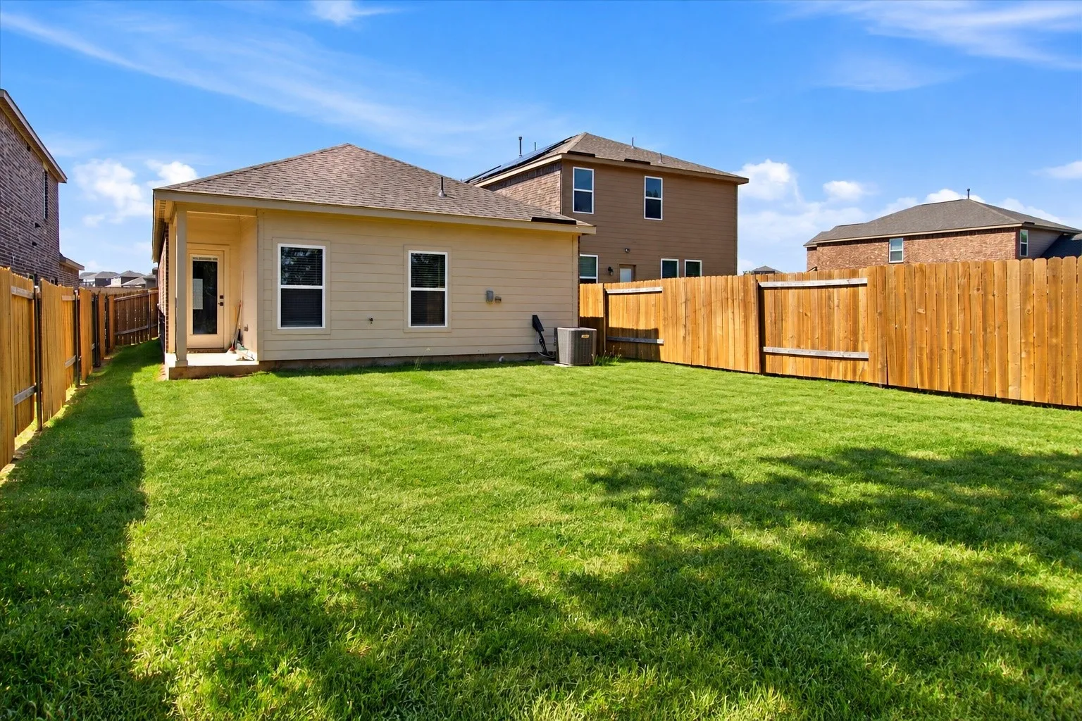 Expansive grassy yard with a full privacy fence