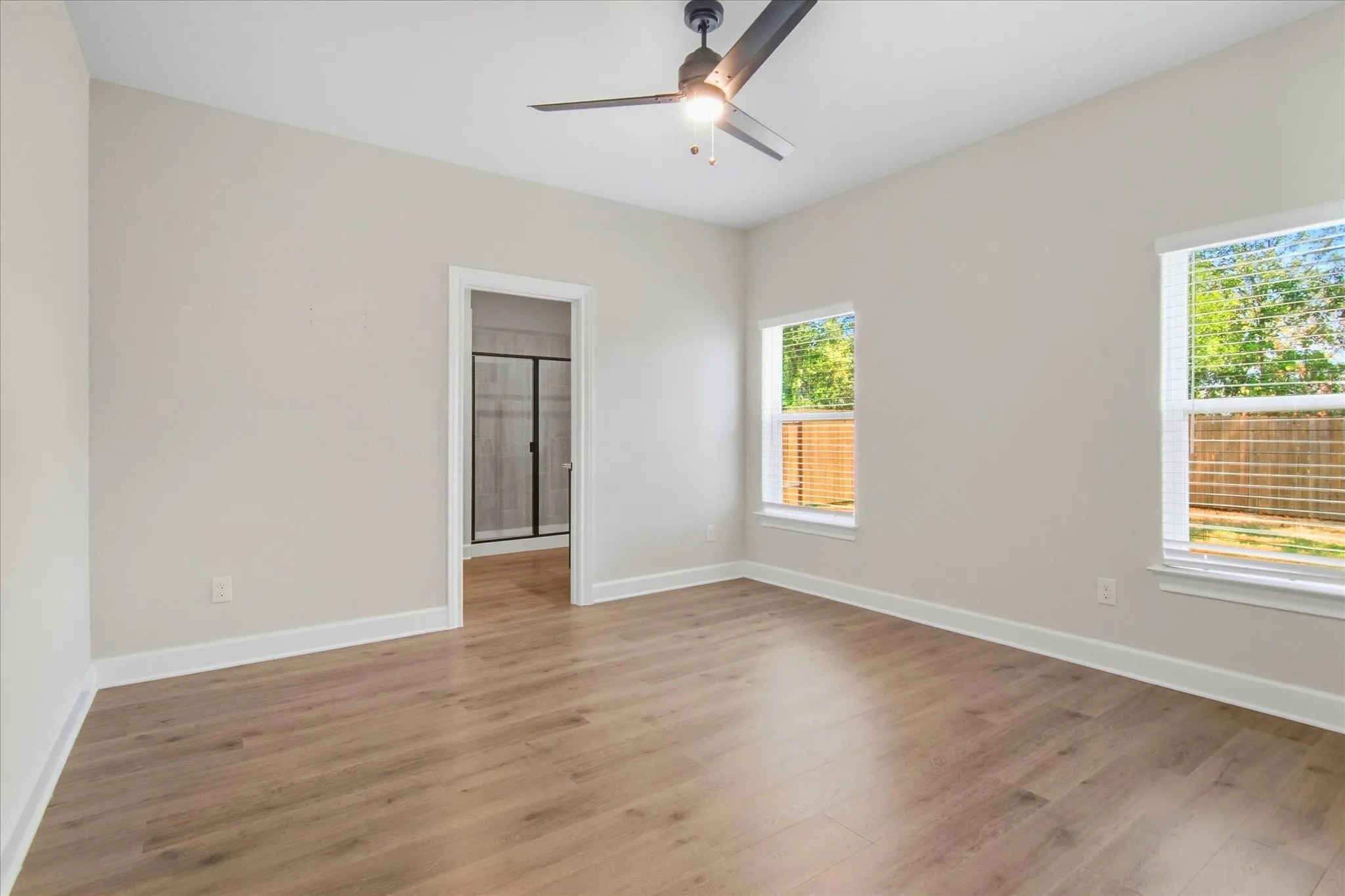Recessed lighting, wood-finish flooring, two windows with blinds, a ceiling fan, and access to an en-suite bathroom