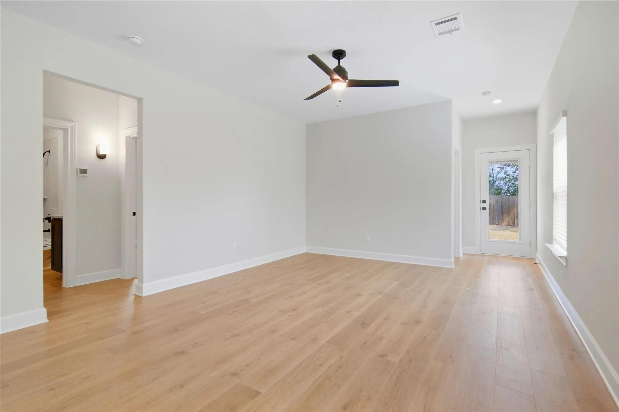 Open concept room with wood-finish flooring, a contemporary ceiling fan, and access to an outdoor area